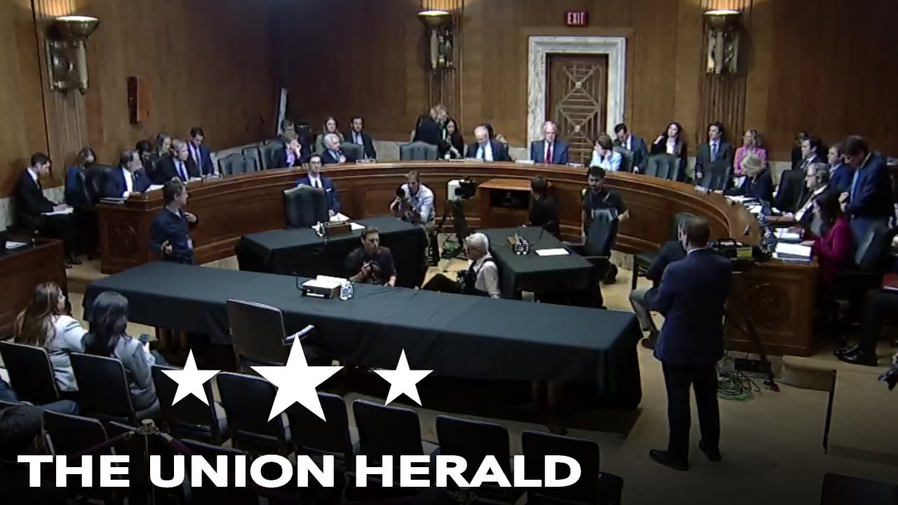 A Senate Judiciary Committee hearing room with senators seated at the dais and witness table in the foreground, news photography style