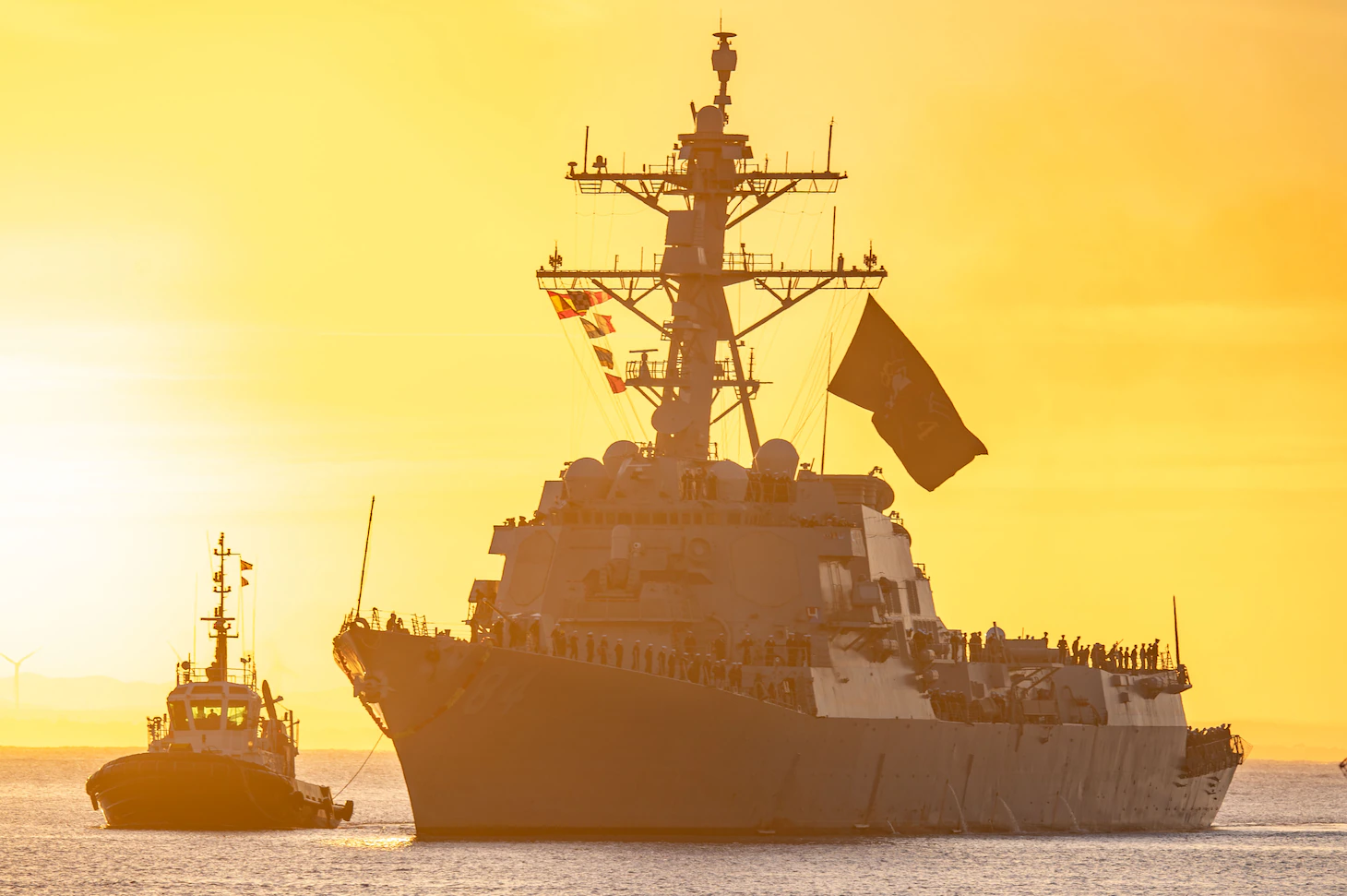 A U.S. Navy destroyer underway at sunset during a maritime patrol, news photography style