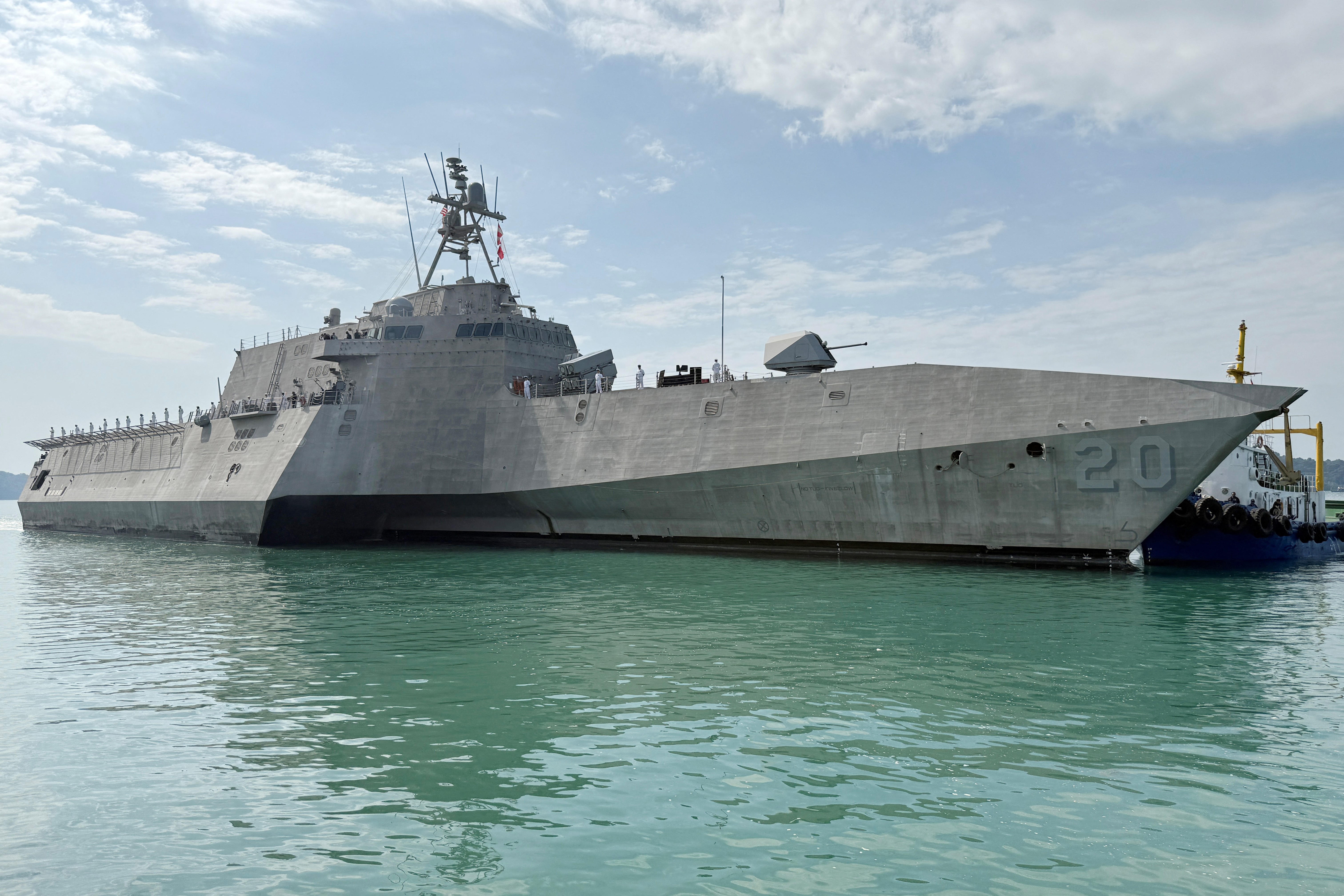 A U.S. Navy warship moving through open water in the Persian Gulf under bright sun, news photography style