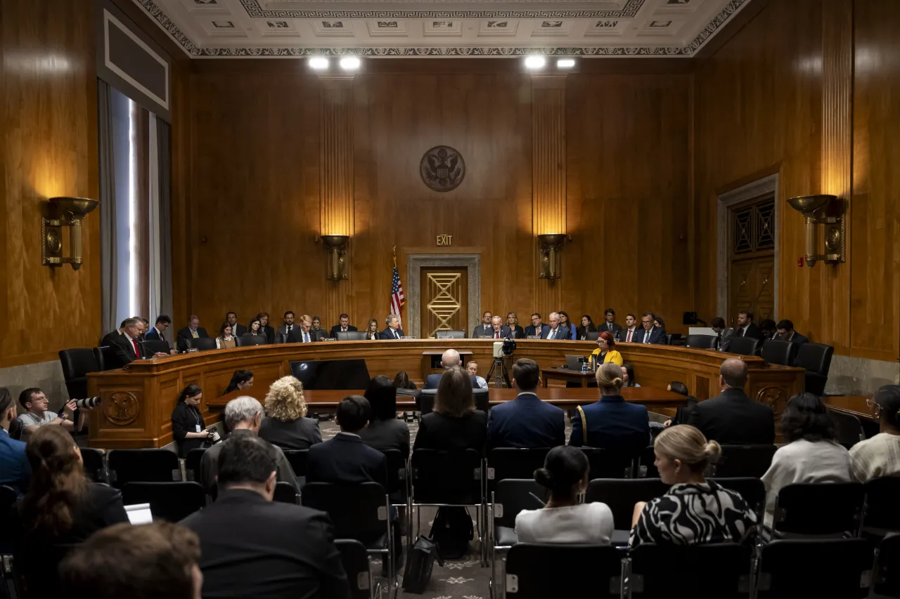 A U.S. Senate committee hearing room with senators seated at the dais during a Department of Homeland Security confirmation hearing, microphones and nameplates visible, news photography style