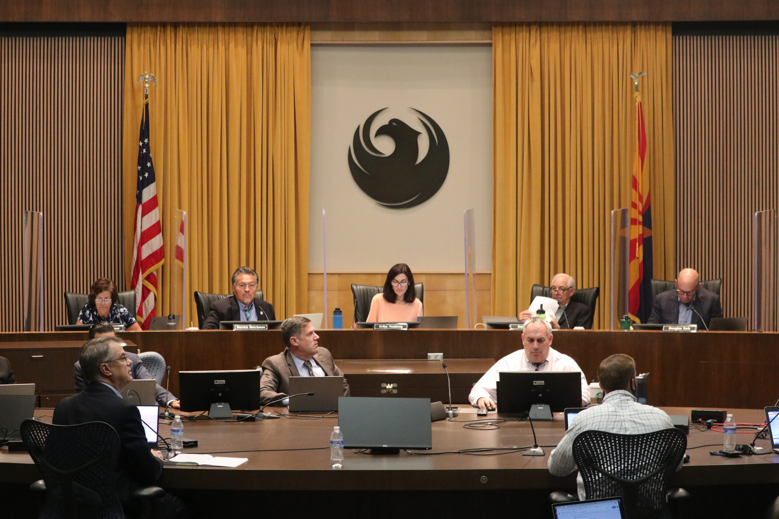 A citizens redistricting commission meeting in Phoenix, Arizona in October 2020, with commissioners seated at a long table and members of the public watching, realistic indoor event photography
