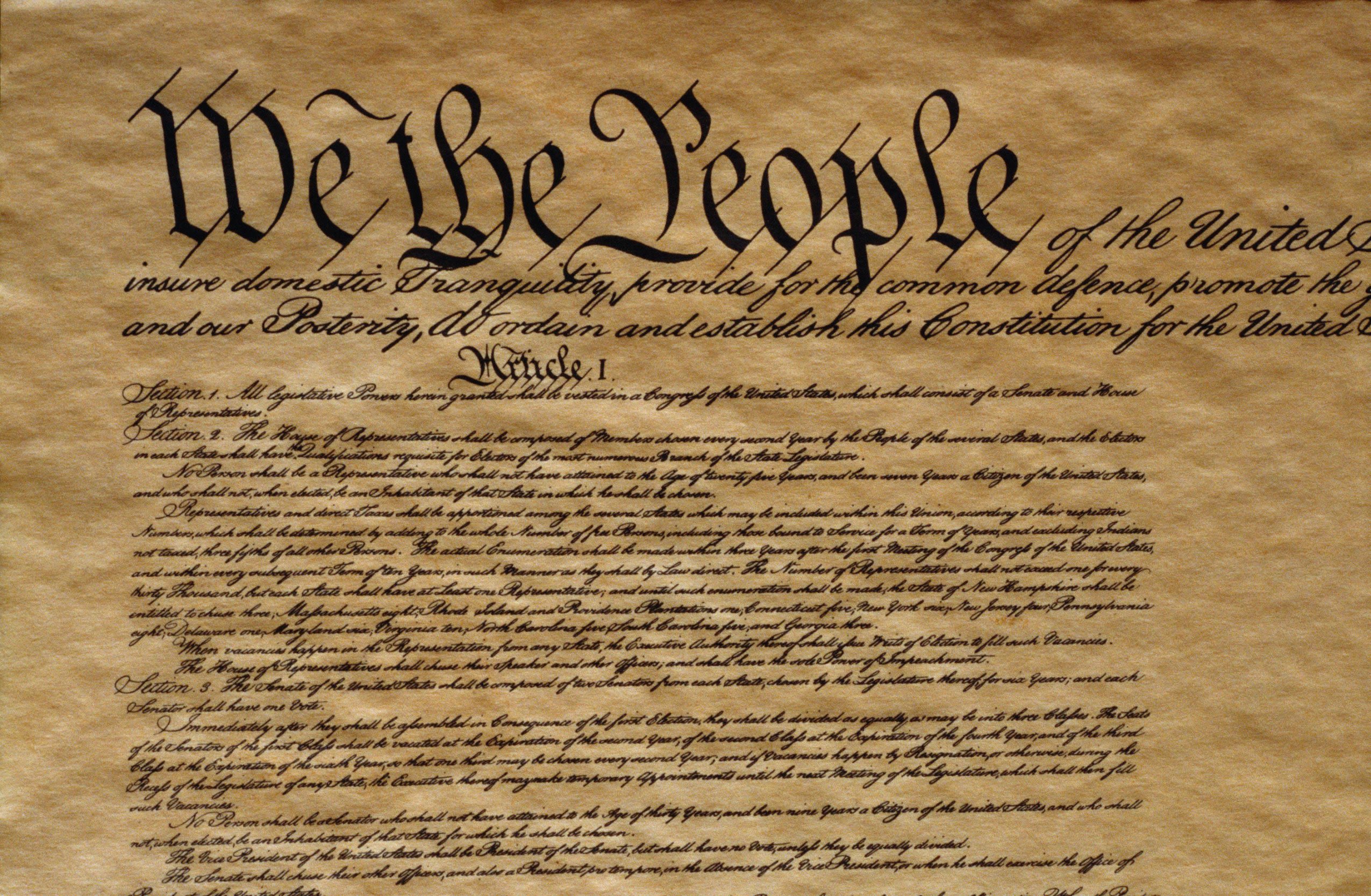 A close photograph of the United States Constitution on display, focused on Article I text associated with congressional powers and protections
