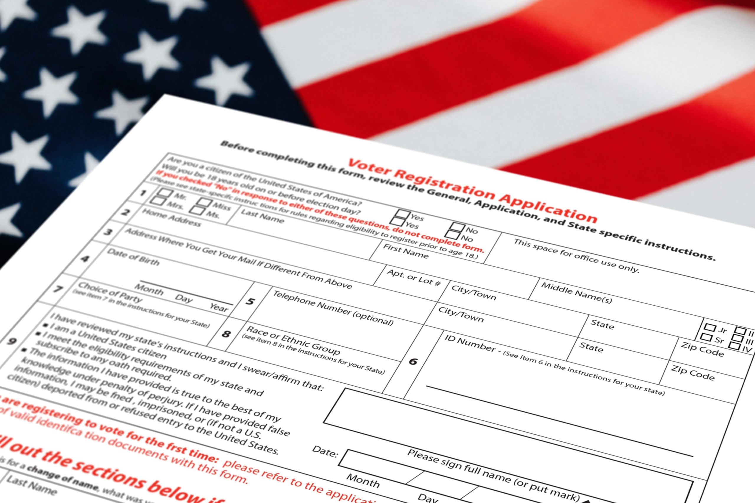 A close-up photo of a person holding voter registration paperwork and a United States passport on a desk, realistic documentary news photography style