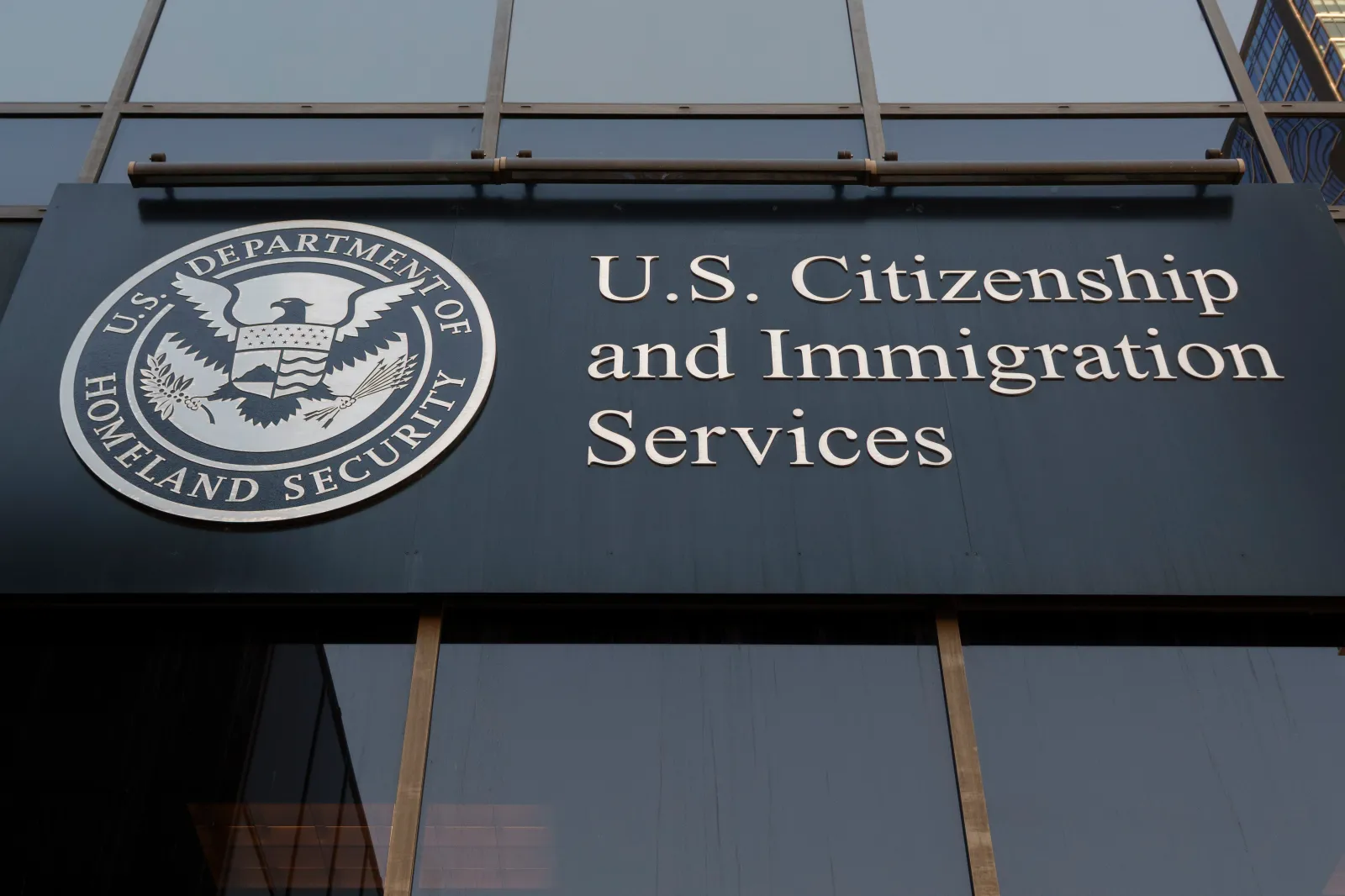 A close-up photograph of the U.S. Citizenship and Immigration Services seal on a wall inside a federal building