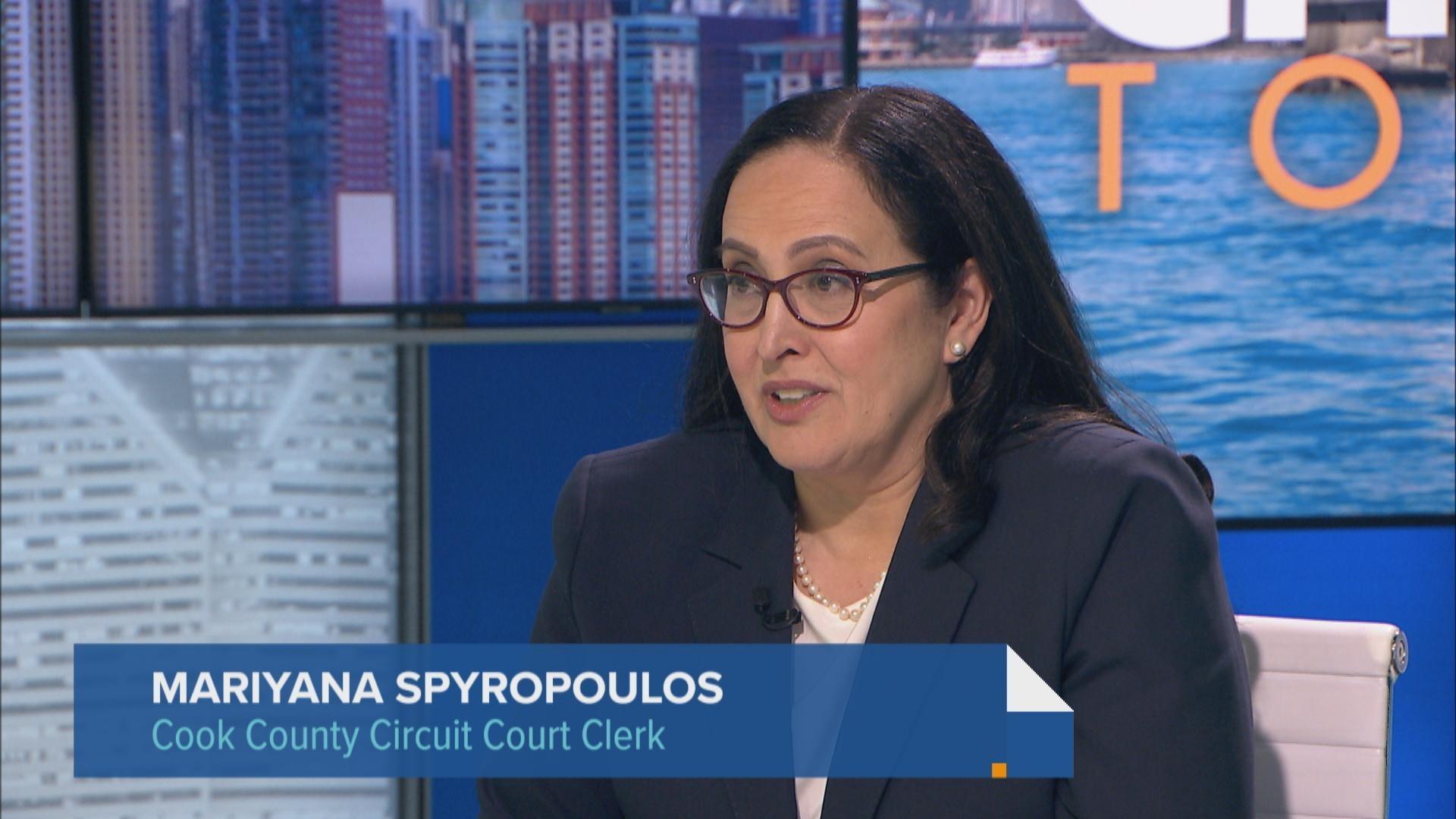 A county court clerk office counter with a clerk processing paperwork and a visitor presenting documents, photographed in a realistic documentary style
