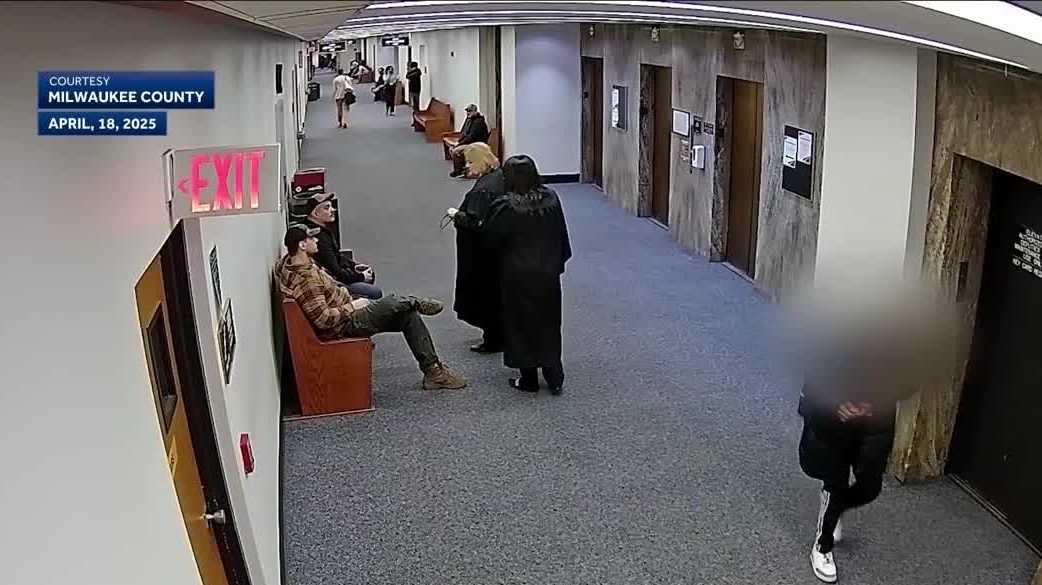 A county prosecutor in a courthouse hallway holding a thick case file folder, news photography style