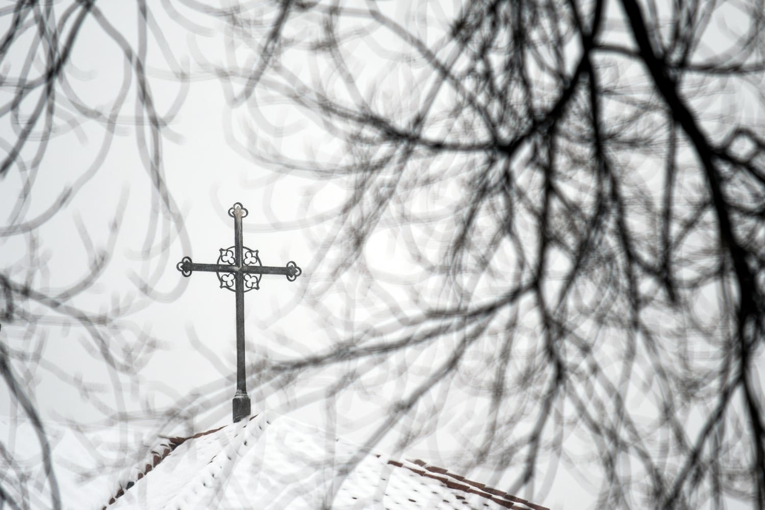 A cross mounted on a building at a Catholic campus in the Denver area on a clear day, news photography style