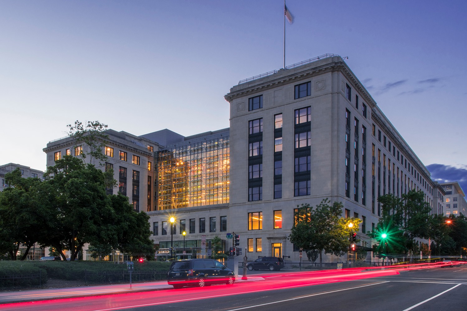 A daytime street-level photograph of a federal courthouse building in Fort Worth with people walking near the entrance and flags on poles outside, news photography style