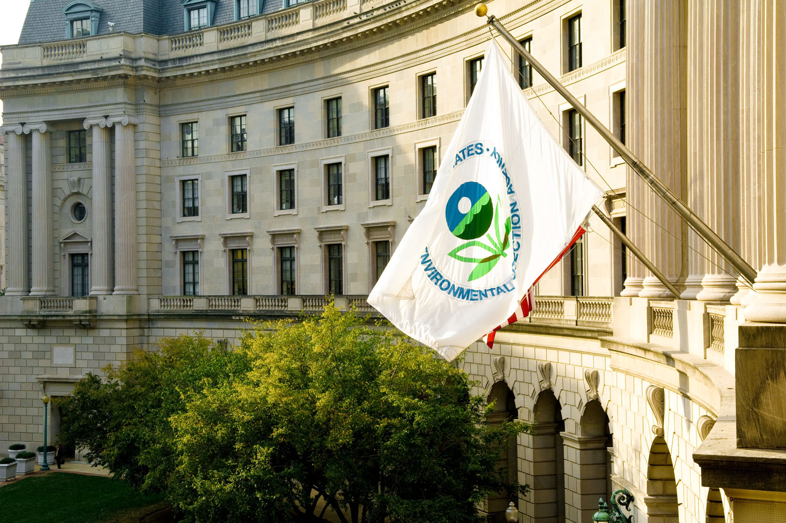 A documentary-style photograph of the Environmental Protection Agency headquarters building in Washington, DC with pedestrians walking past the entrance