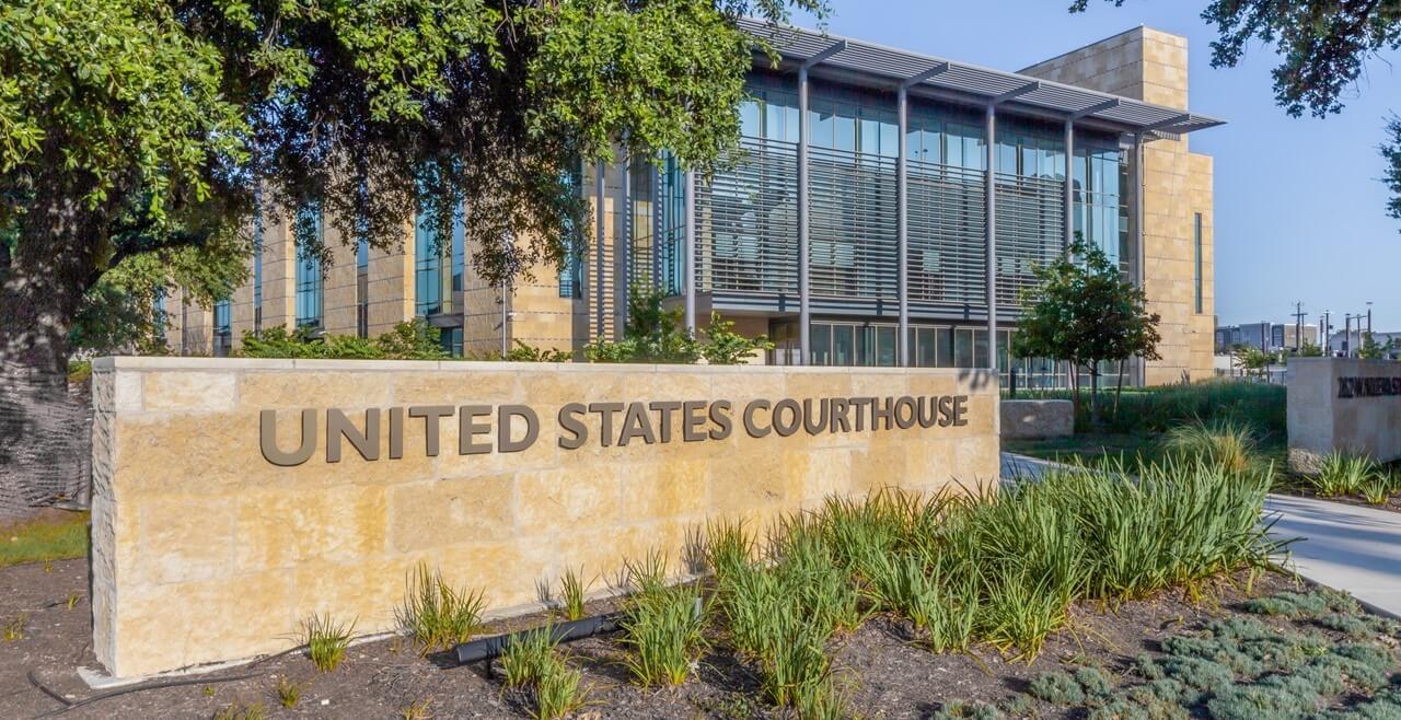 A federal courthouse building exterior with signage and columns, photographed in daylight