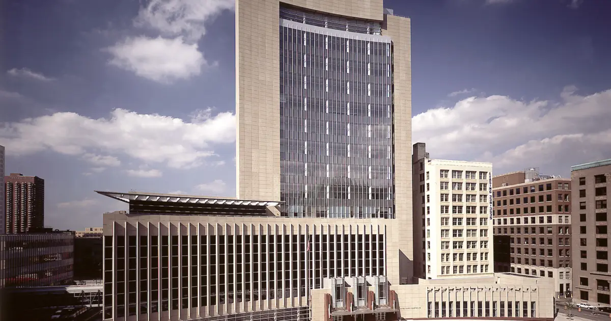 A federal courthouse in Minnesota on an overcast day, with the building entrance and American flag visible, photorealistic news photography