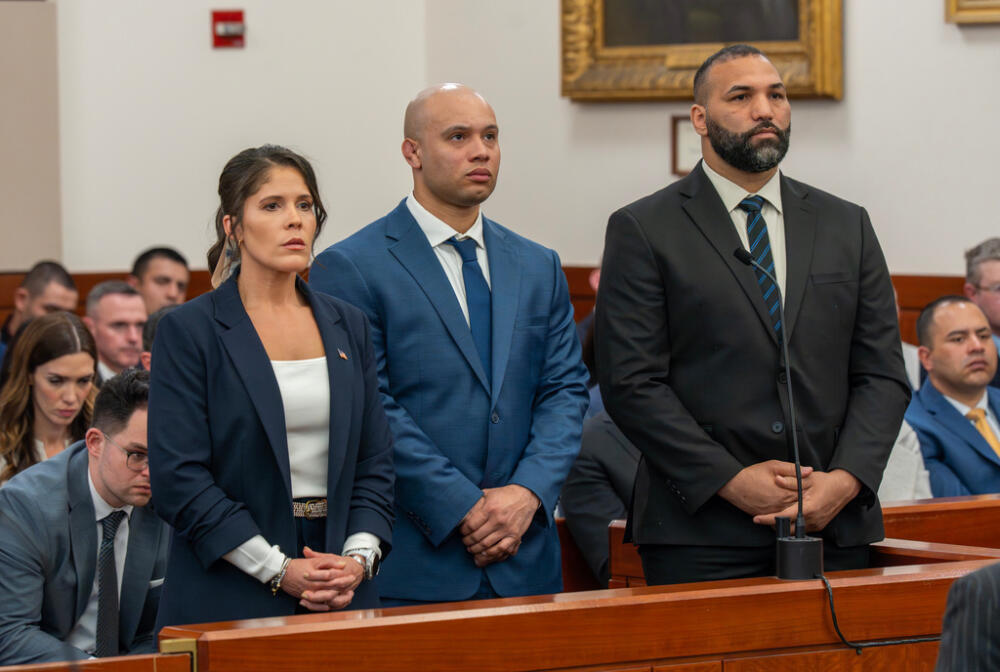 A federal courtroom during an arraignment in a United States District Court, with the judge on the bench and attorneys standing at counsel tables, news photography style