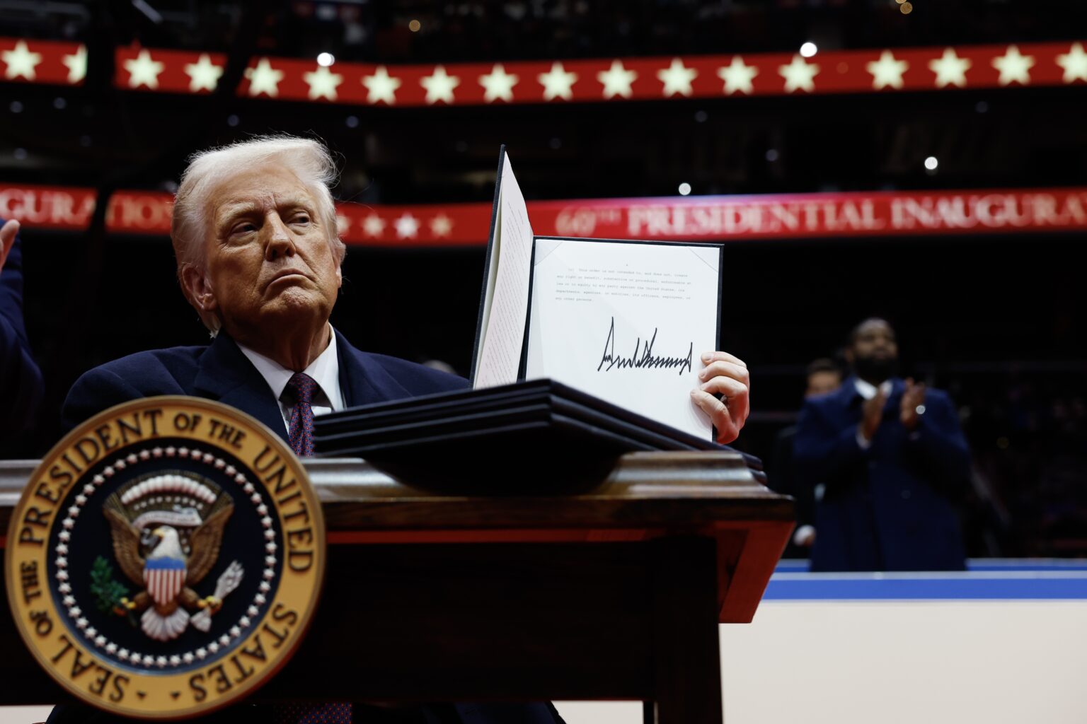 A federal employee in an office in Washington, D.C. reviewing printed pages of the Federal Register at a desk, realistic news photography style