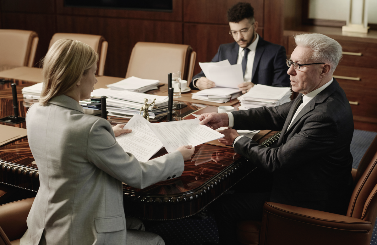 A federal public defender speaking with a client at a table inside a courthouse attorney-client meeting room, news photography style