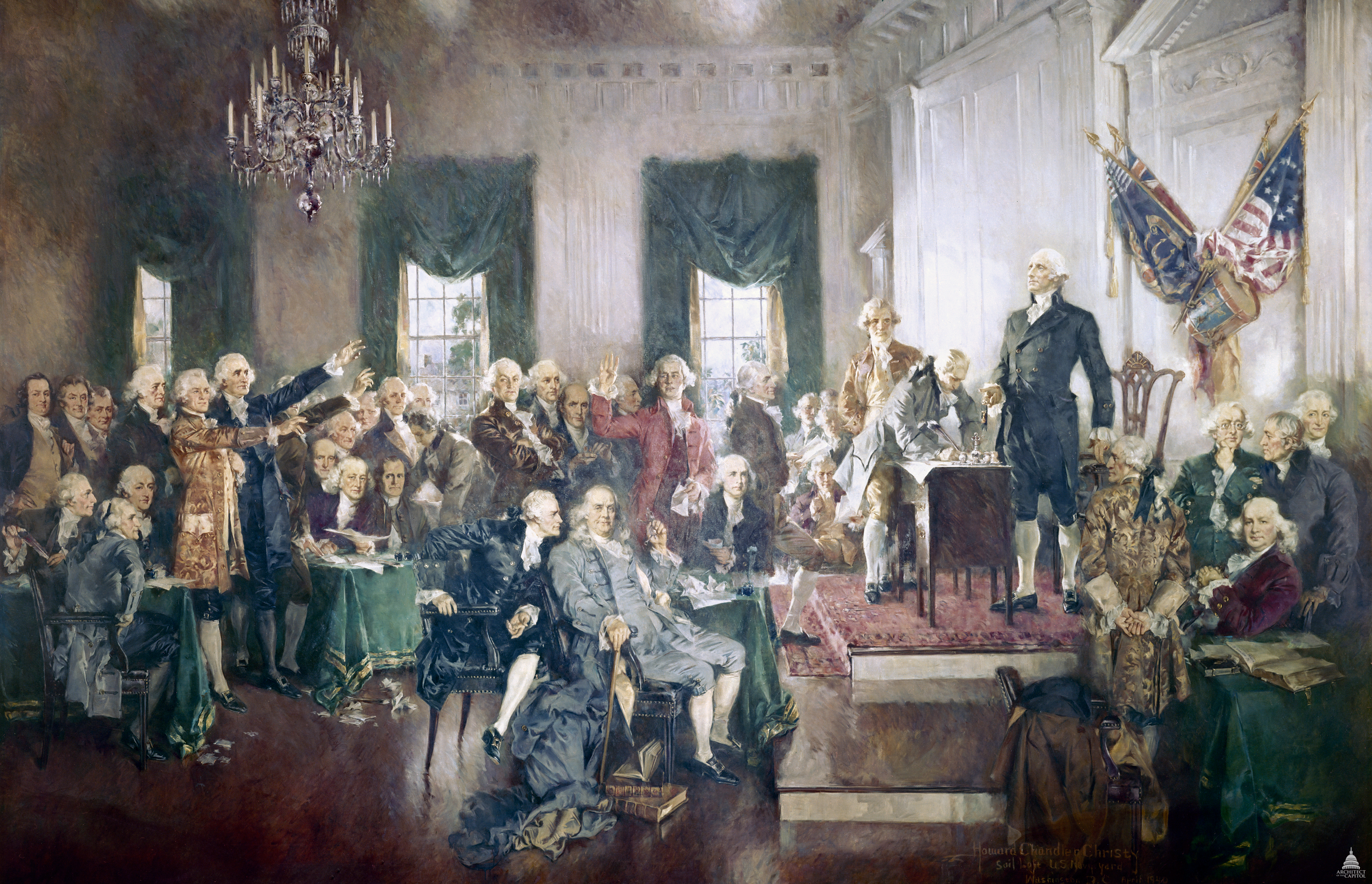 A historical reenactment style photograph of delegates seated inside Independence Hall in Philadelphia during the Constitutional Convention, with papers on desks and warm window light