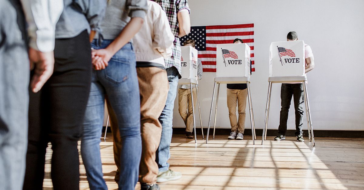 A line of voters waiting outside a local polling place in the United States on election day, with a civic building entrance in the background