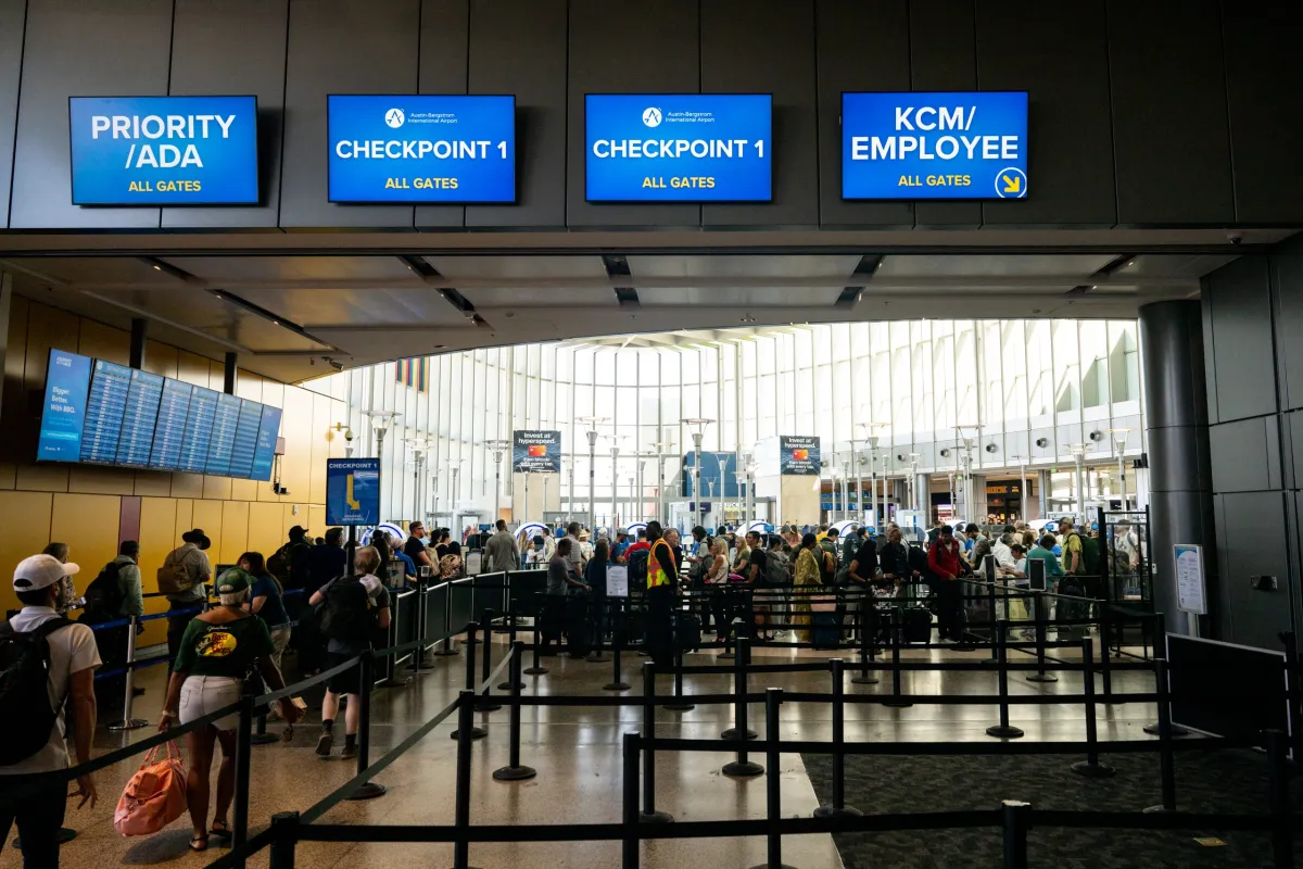 A long line of travelers waiting at an airport security checkpoint early in the morning, candid news photo style
