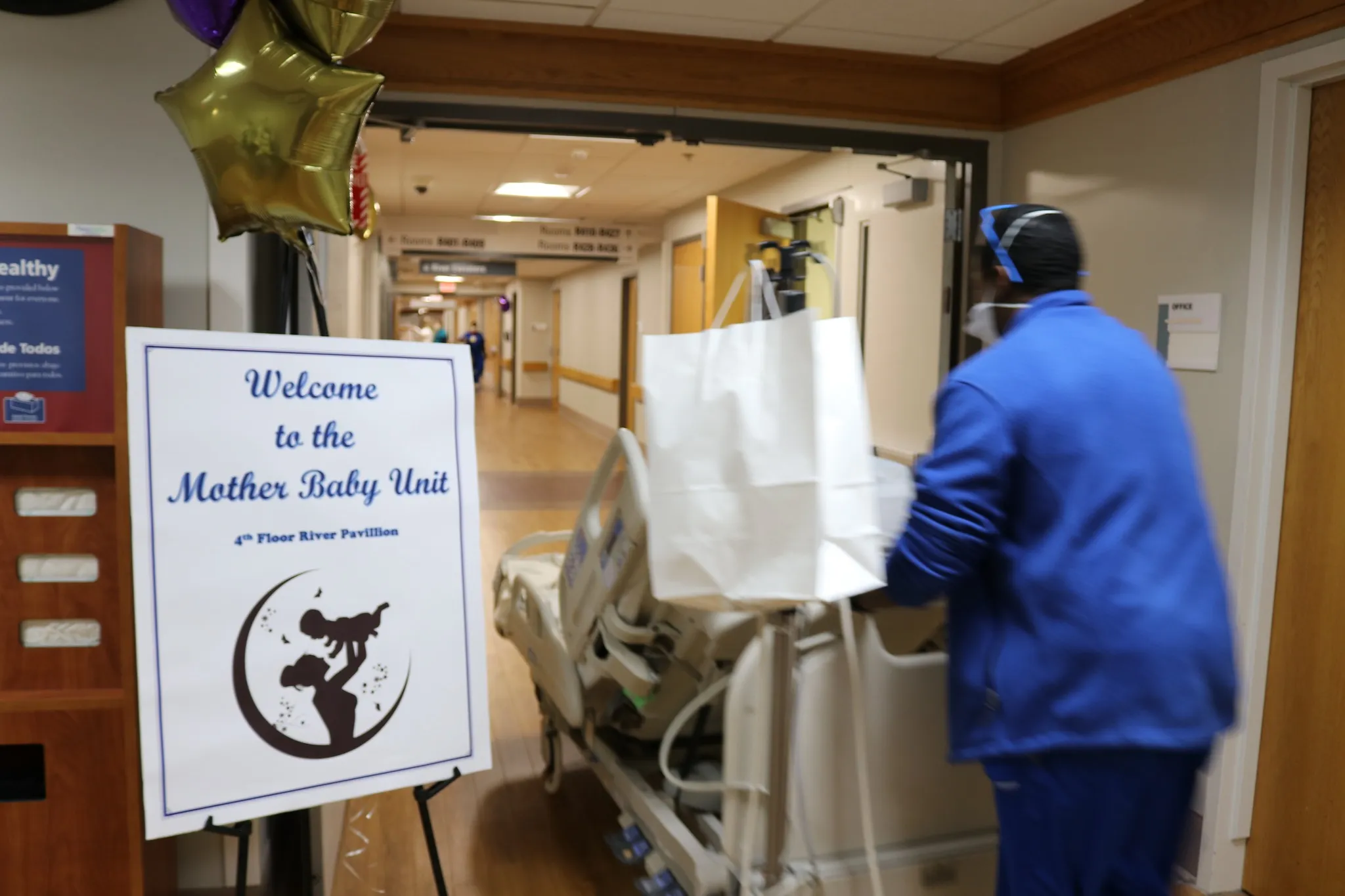 A newborn baby swaddled in a hospital maternity ward in the United States, with a nurse adjusting the blanket, documentary news photography style
