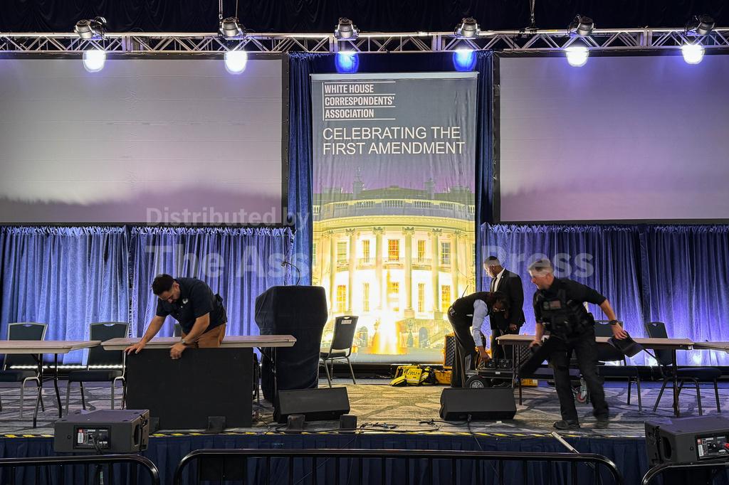 A nighttime photograph of an entrance area near a high-profile political event, with security barriers and law enforcement presence visible, news photography style