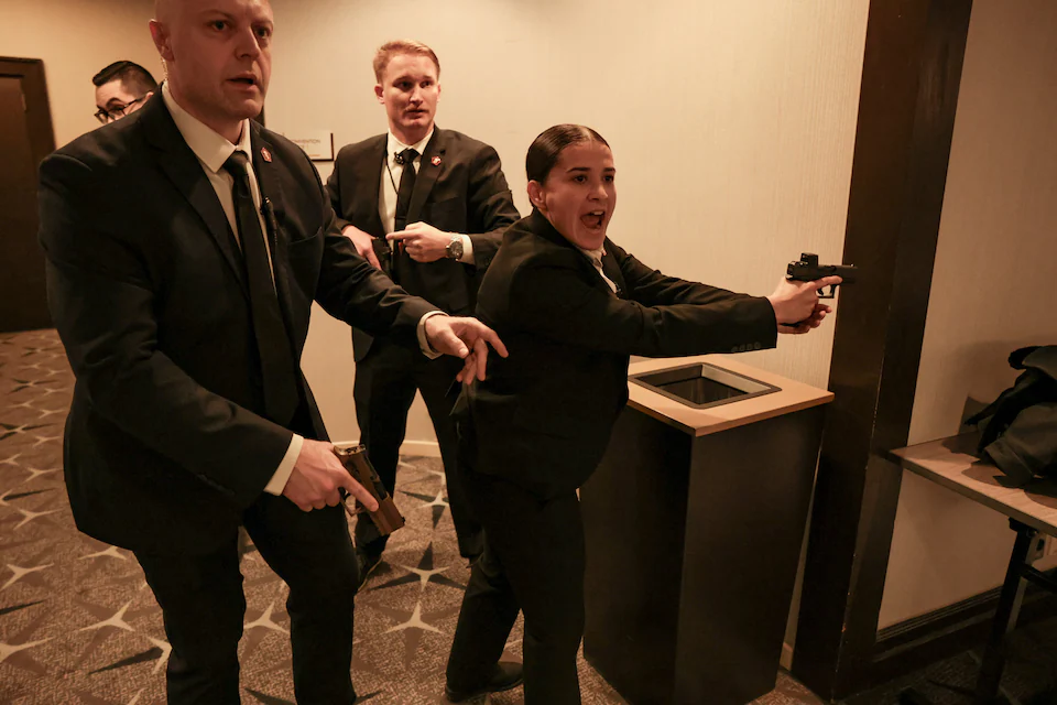 A nighttime street scene outside a Washington, DC hotel hosting a major political media event, with visible security perimeters and attendees in formal wear moving toward the entrance, news photography style