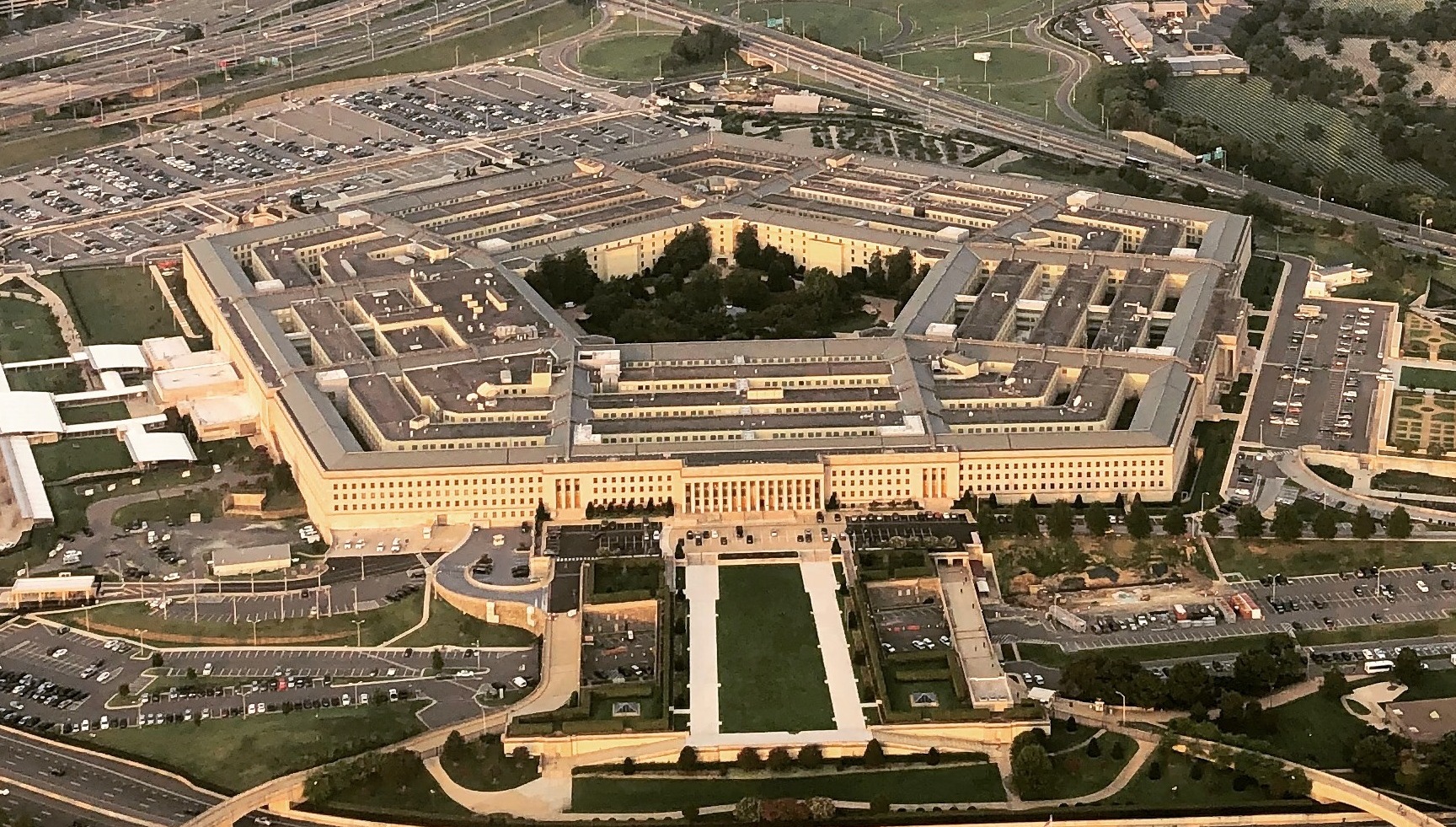 A photograph of the Pentagon exterior in Arlington, Virginia, taken in daylight with security fencing visible