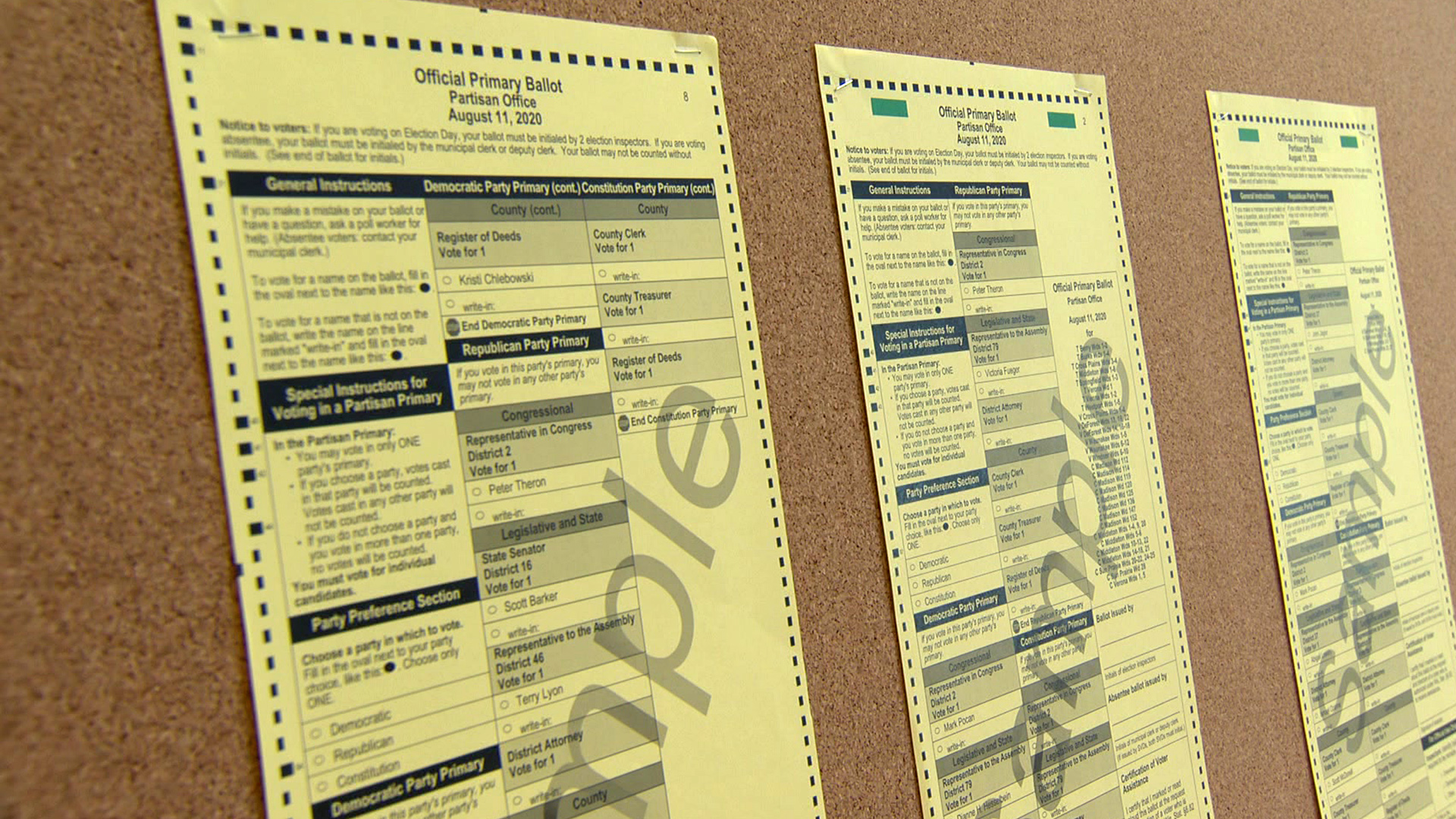 A poll worker handing a paper ballot to a voter at a check-in table inside a city polling place during a ranked-choice election, candid news photo style