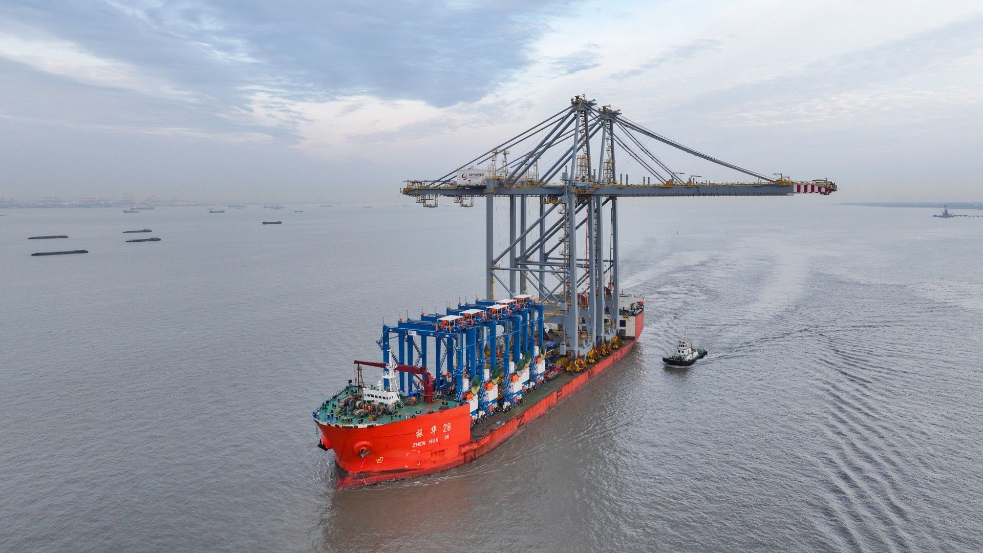 A port crane lifting a cargo container onto a waiting semi truck near a waterfront terminal, realistic news photo