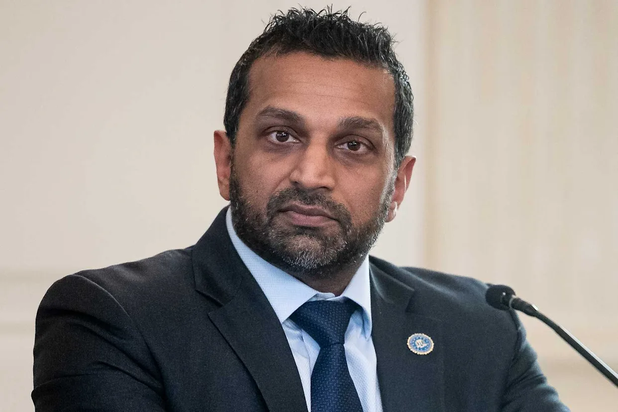 A press conference photograph of FBI Director Kash Patel speaking at a podium with microphones in a government building, news photography style