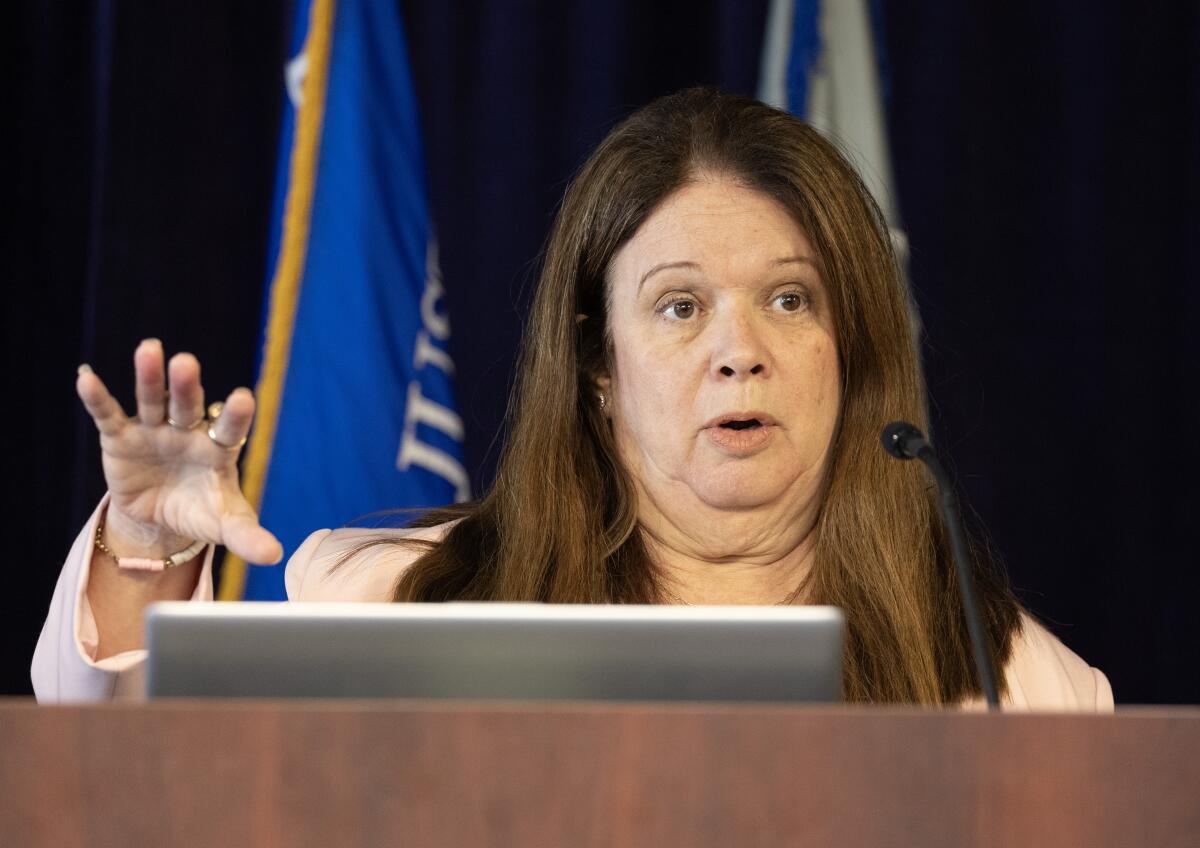 A prosecutor in an office reviewing a case file at a desk with courthouse buildings visible through a window, candid news photo style