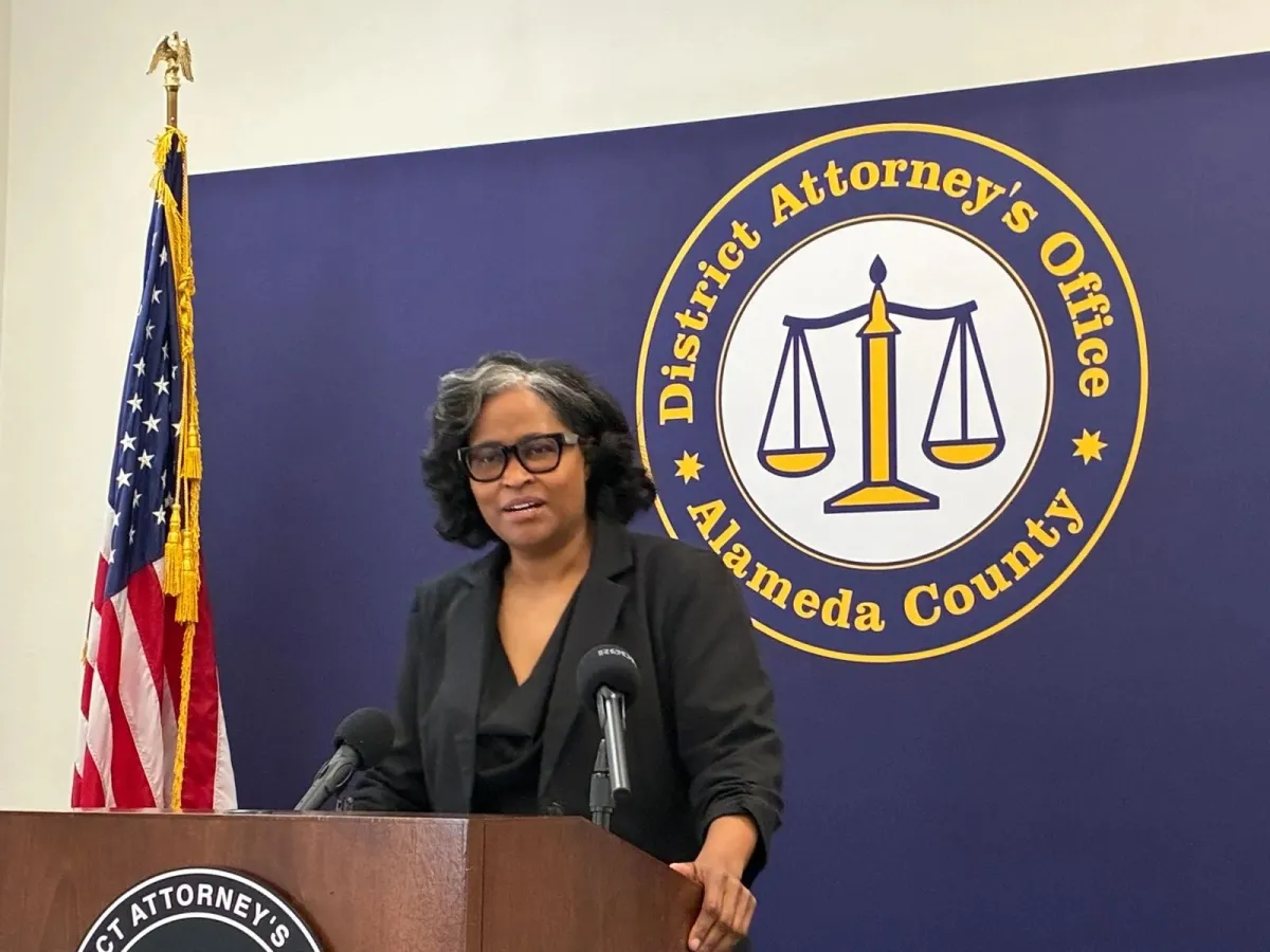 A prosecutor reviewing a thick case file at a desk in a county courthouse office, with folders and evidence envelopes visible in the background, documentary-style photography