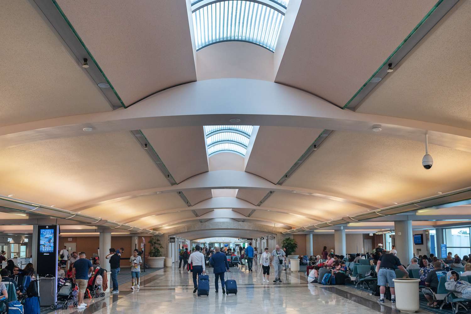 A public airport terminal concourse with travelers moving through the space