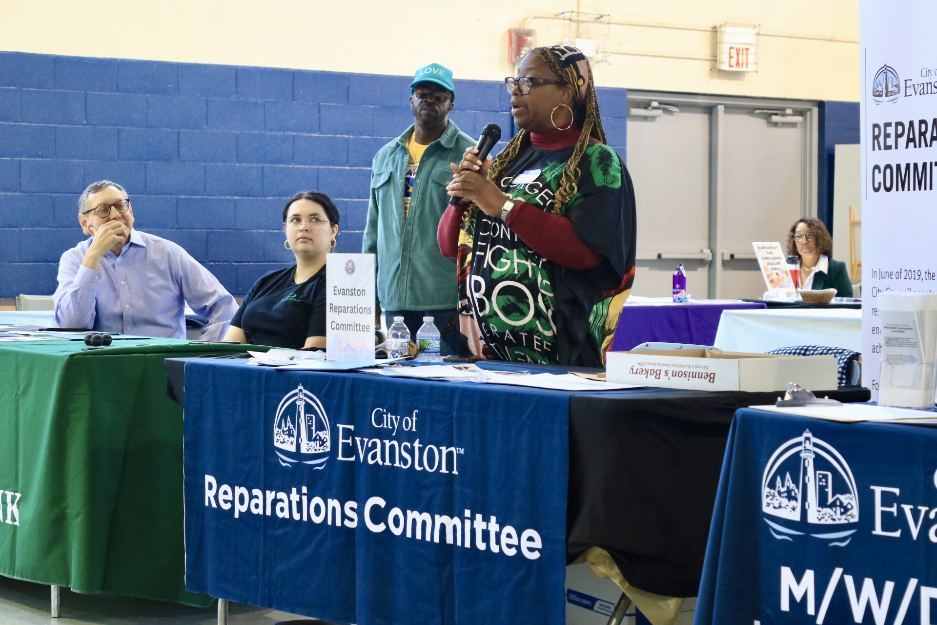A public meeting room in Evanston, Illinois during a city committee session, with residents seated and officials at a dais, news photography style
