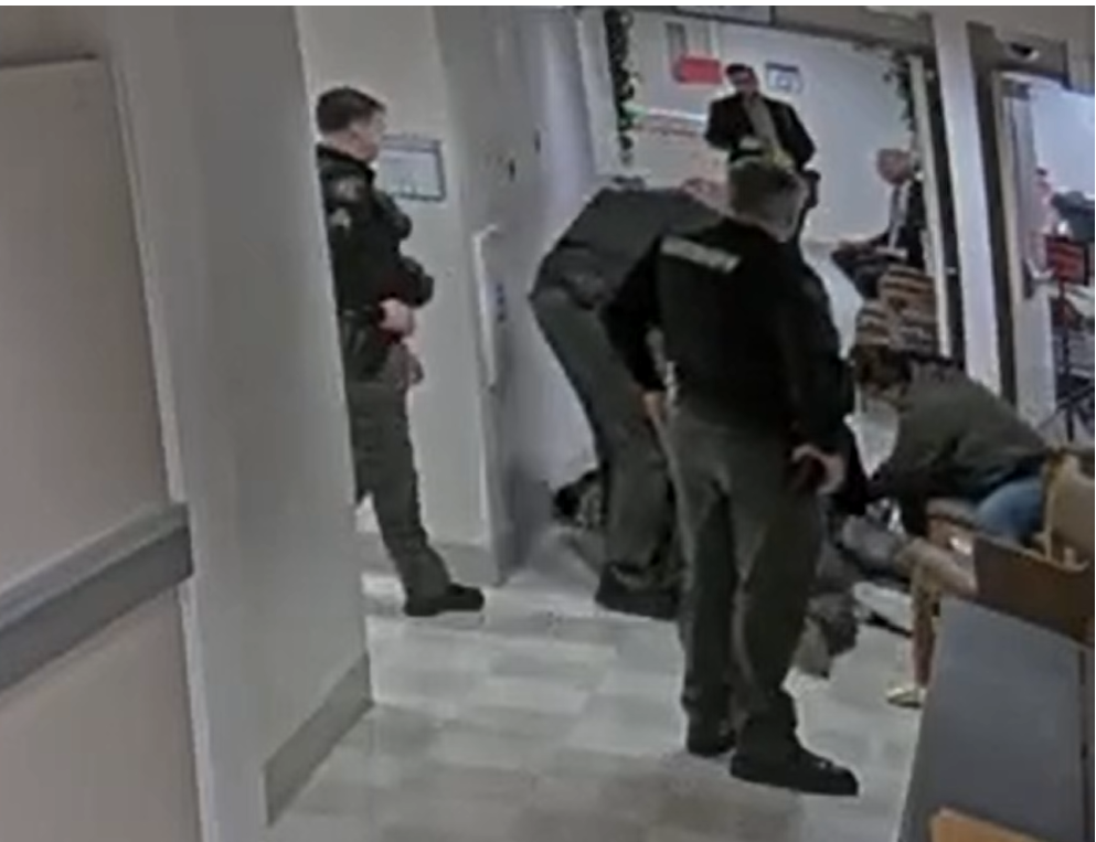 A quiet courthouse hallway with wooden benches and a closed courtroom door, with a few people seated and waiting, realistic photography
