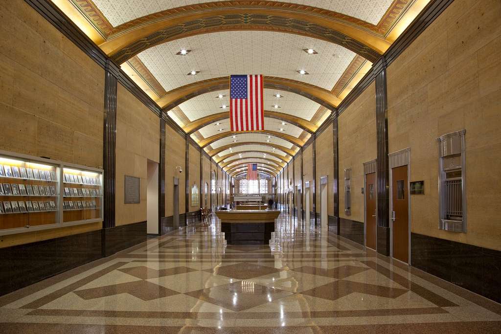 A quiet hallway inside a United States federal courthouse with courtroom doors and soft overhead lighting, realistic news photo