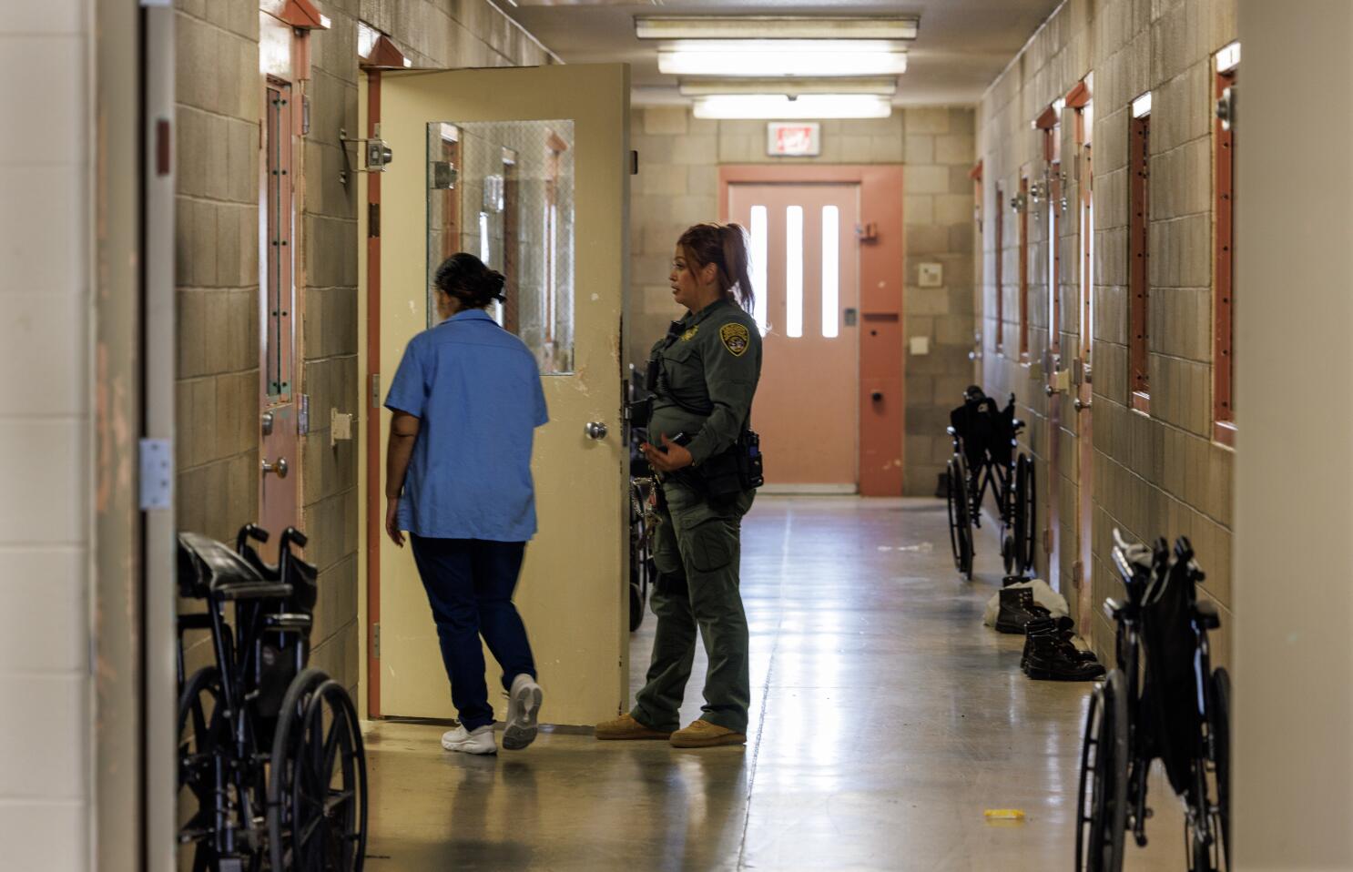 A quiet hallway inside a federal prison medical unit with closed doors and fluorescent lighting, photographed in a realistic news style