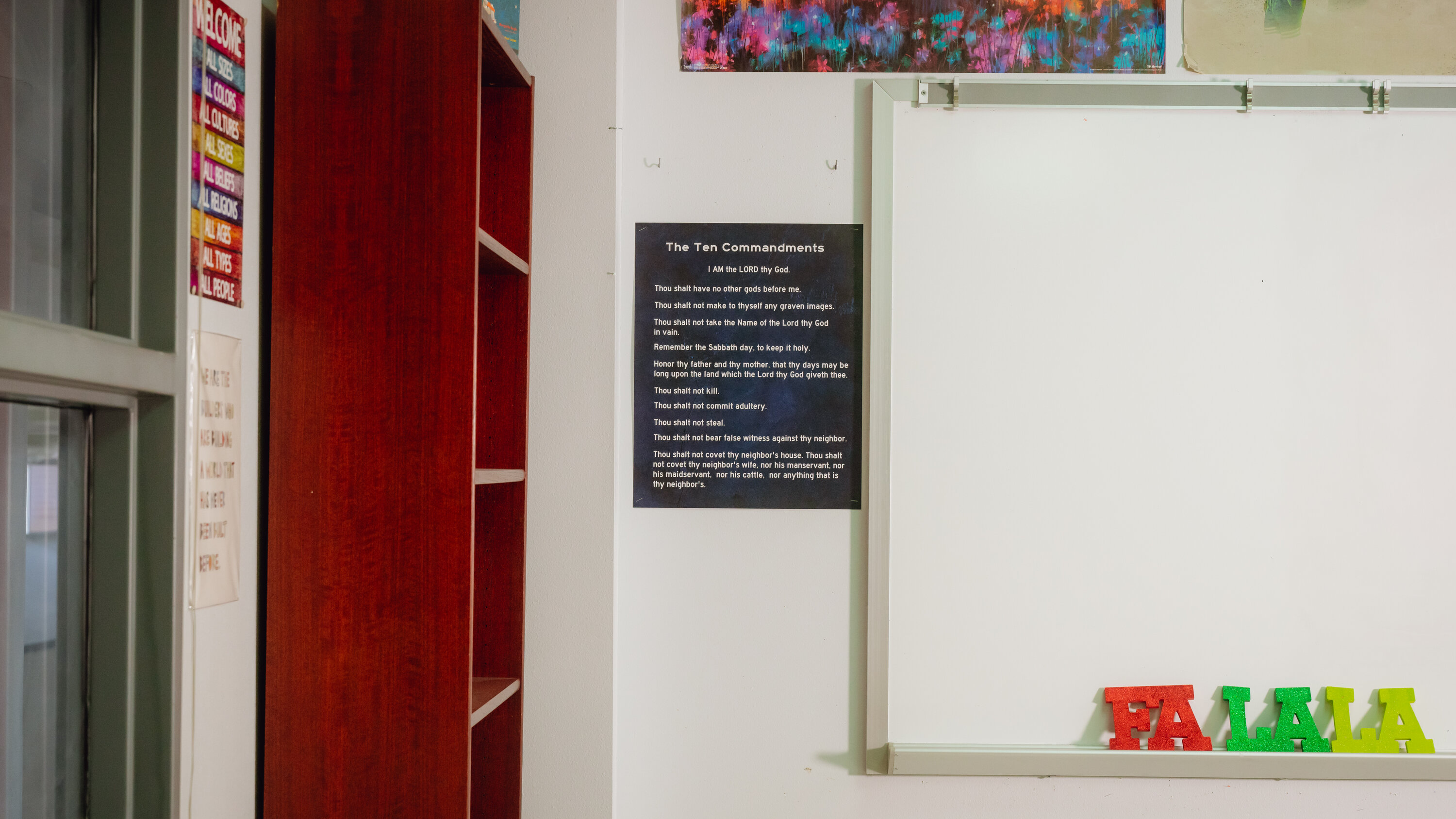 A real Texas public school classroom with desks and a whiteboard, showing a framed poster on the wall near the front of the room, news photography style