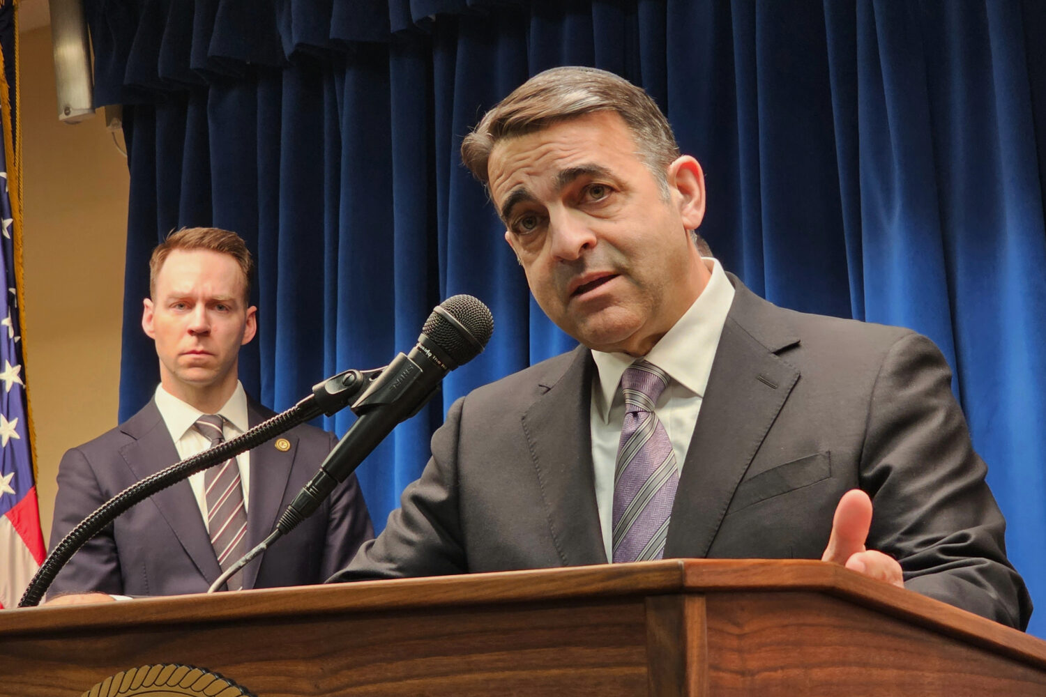 A real federal courtroom scene with an attorney standing at a podium while a judge listens from the bench, documentary news photography style