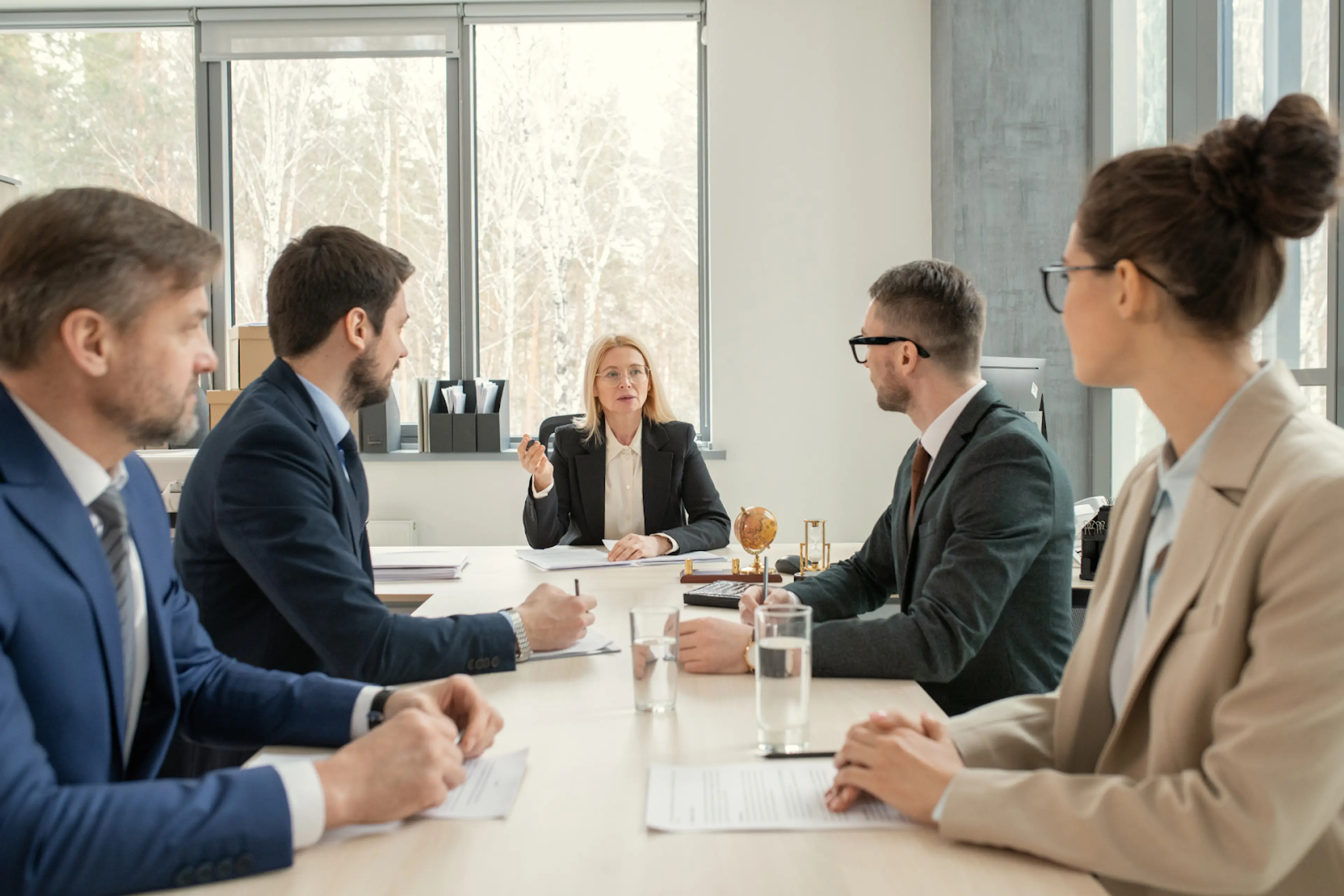 A real photo of political consultants seated around a conference table reviewing campaign compliance documents on laptops and paper printouts