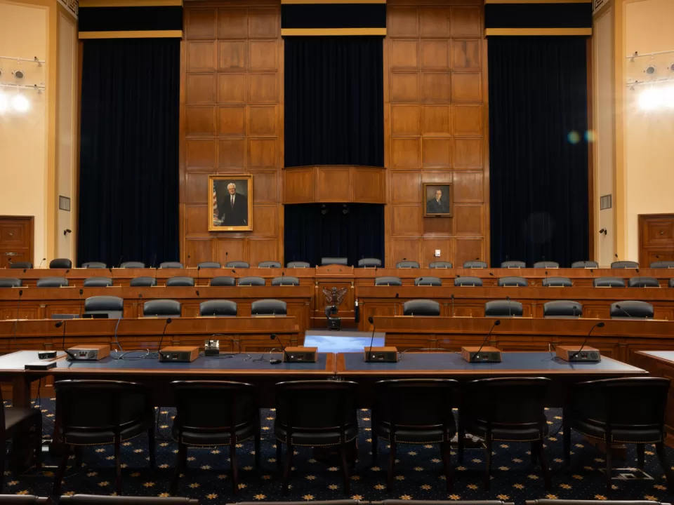 A real photograph of a congressional meeting room with lawmakers seated at a long table during a formal negotiation session, news photography style