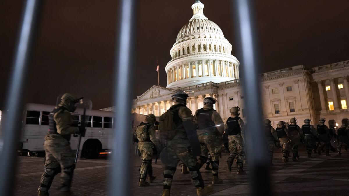 A real photograph of members or staff walking quickly through the United States Capitol corridor in the evening light, suggesting urgency before a floor vote