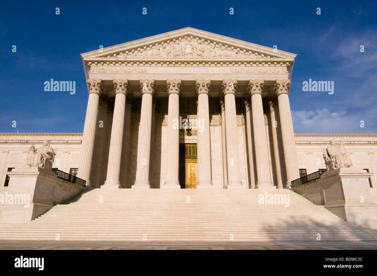 A real photograph of the United States Supreme Court building steps on a bright afternoon, with pedestrians walking past the columns