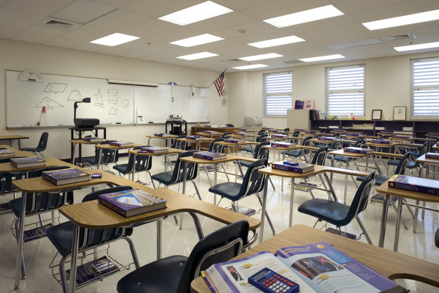 A real public school classroom during the school day with a teacher at the front and students seated at desks, candid documentary photography style