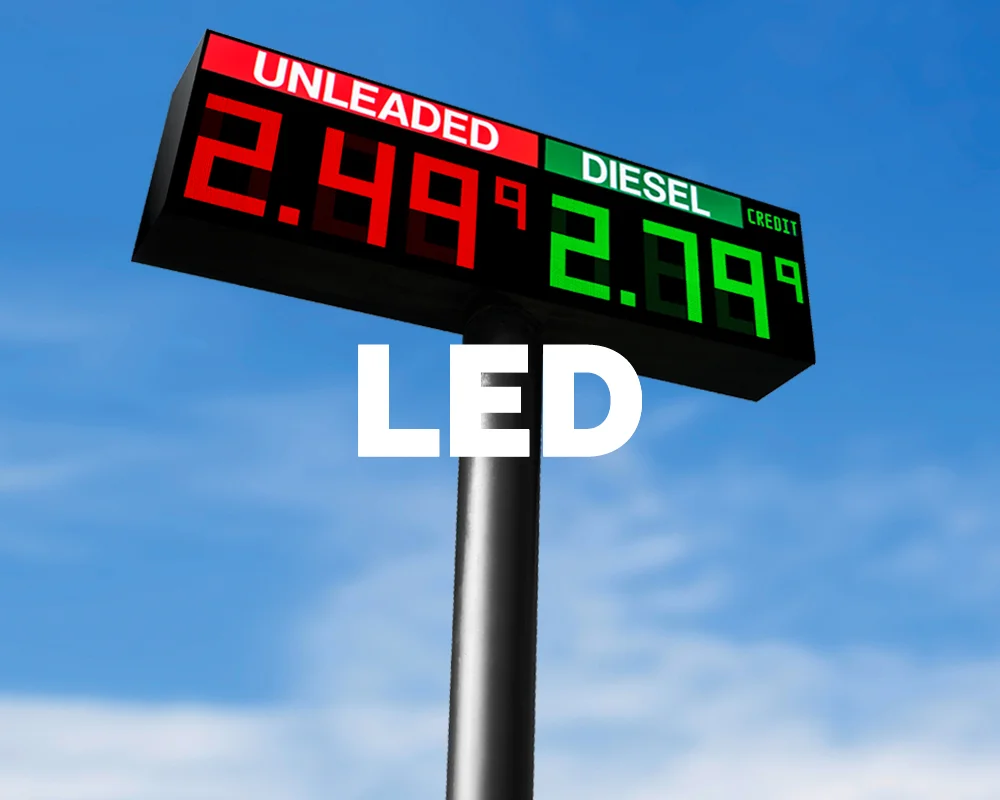 A roadside gas station price sign showing elevated gasoline and diesel prices, photographed at dusk with cars passing in the background, realistic news photography