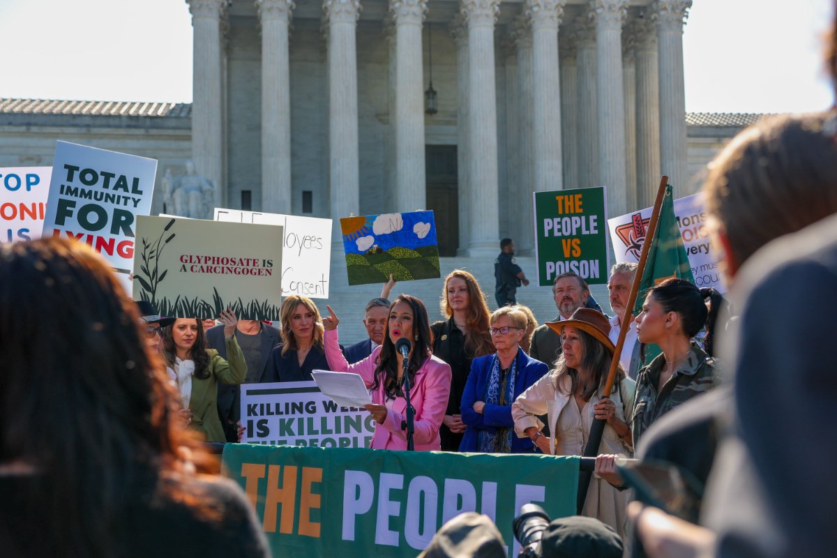 A small crowd of demonstrators holding signs outside the U.S. Supreme Court in Washington, DC, with police barricades visible, news photography style