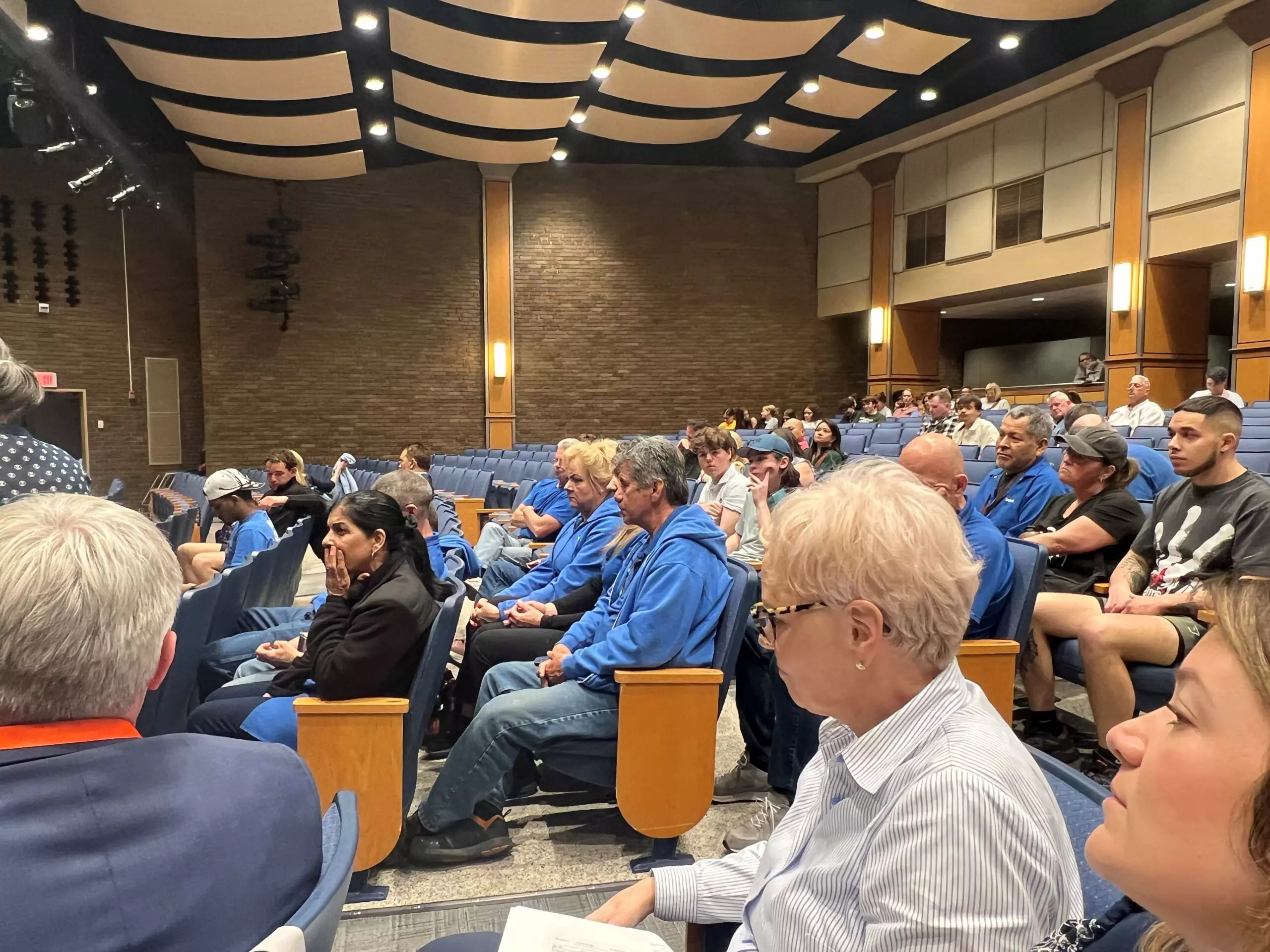 A small group of nonprofit volunteers seated around a table in a New Jersey community center, reviewing papers and a laptop during an evening meeting, news photography style