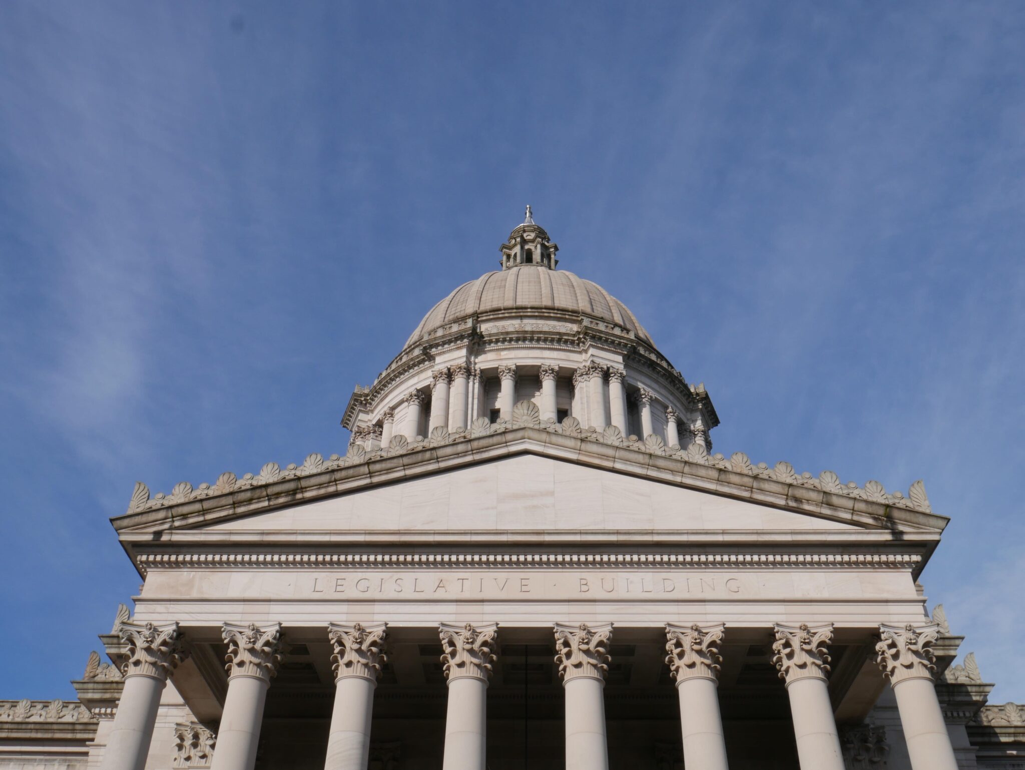 A stack of printed legislative documents and folders on a table inside a government building with the U.S. Capitol visible through a window in Washington, D.C., news photography style