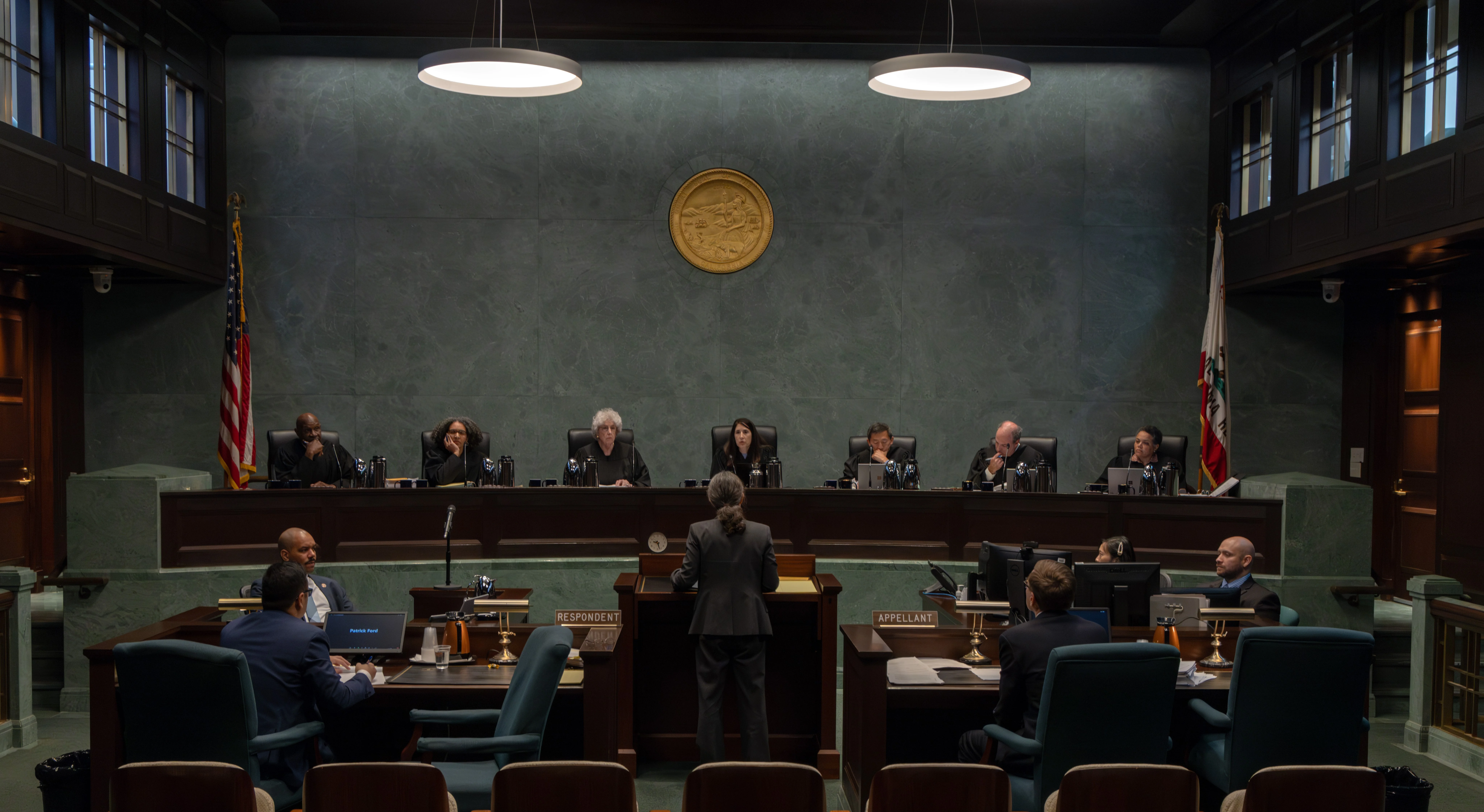 A state supreme court oral argument session with justices seated on an elevated bench and attorneys presenting at a lectern, real news photography style