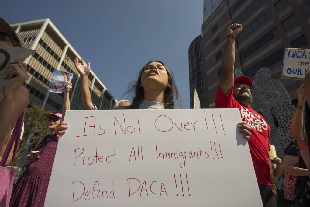 A street scene in Los Angeles in October 2017 with people holding signs at a DACA rally, candid news photography style
