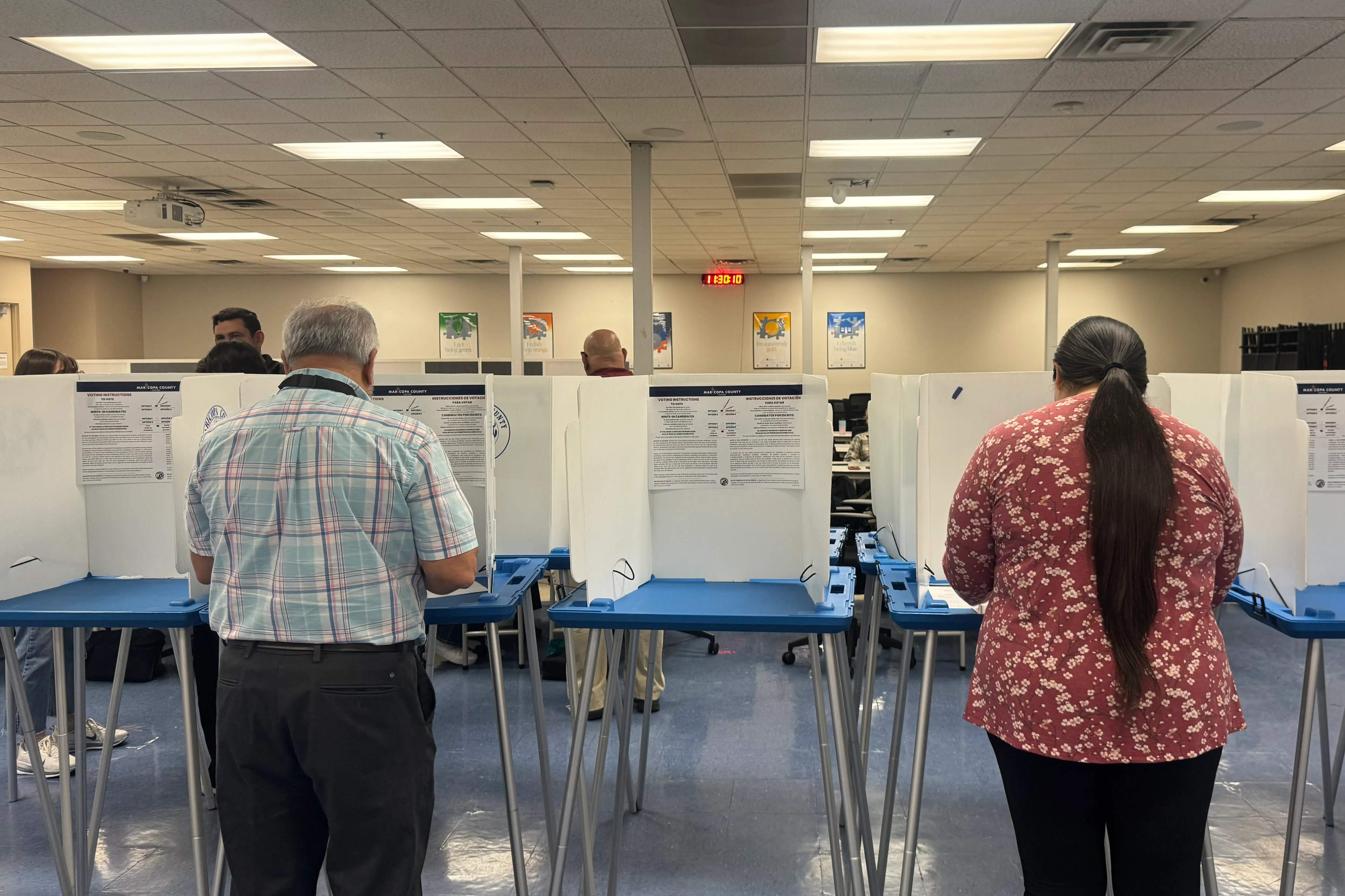 A voter filling out a paper ballot in a private voting booth at a polling place in Phoenix, Arizona during midterm elections, realistic news photo