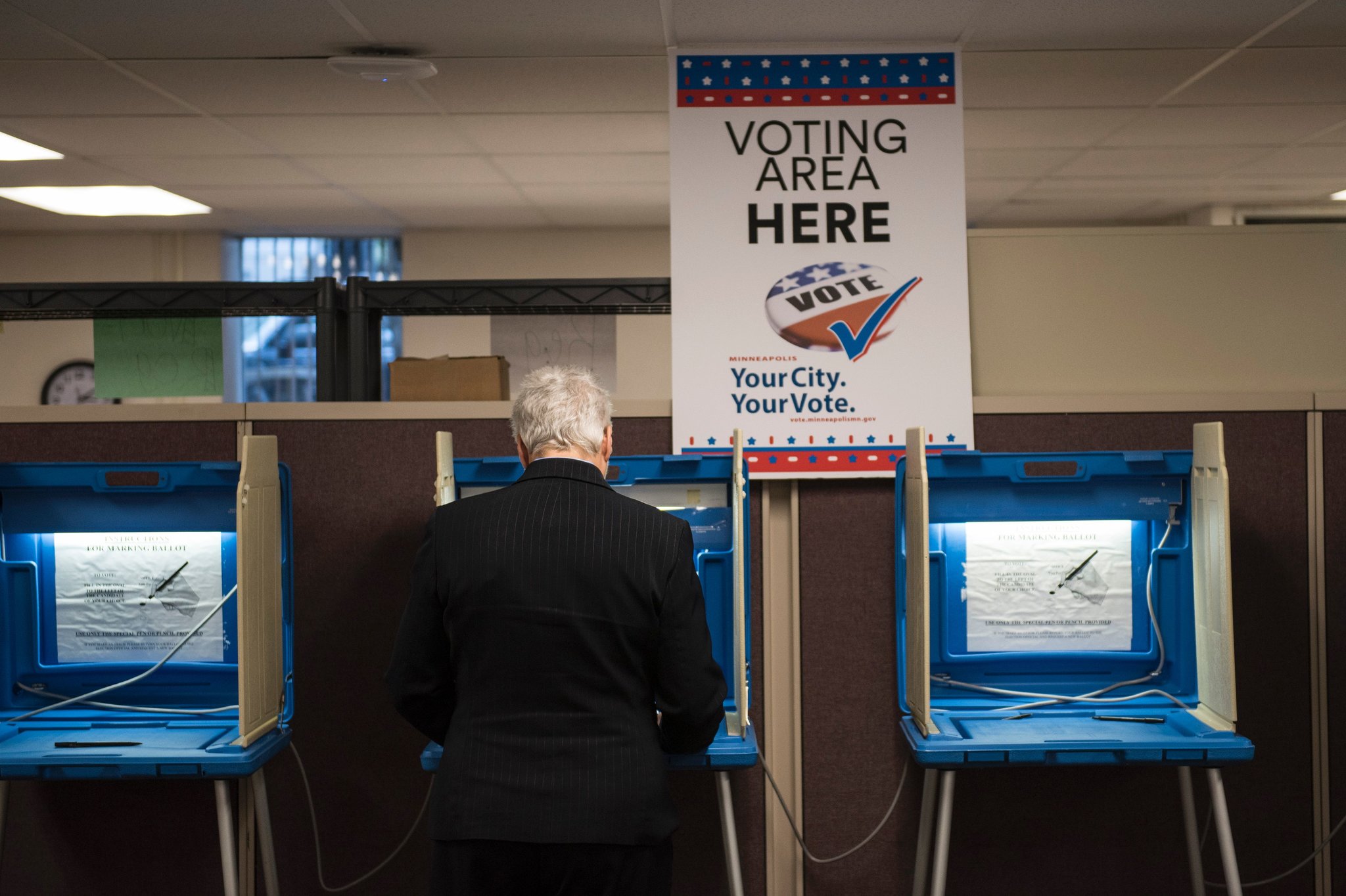 A voter standing at a voting booth filling out a paper ballot at a U.S. polling place